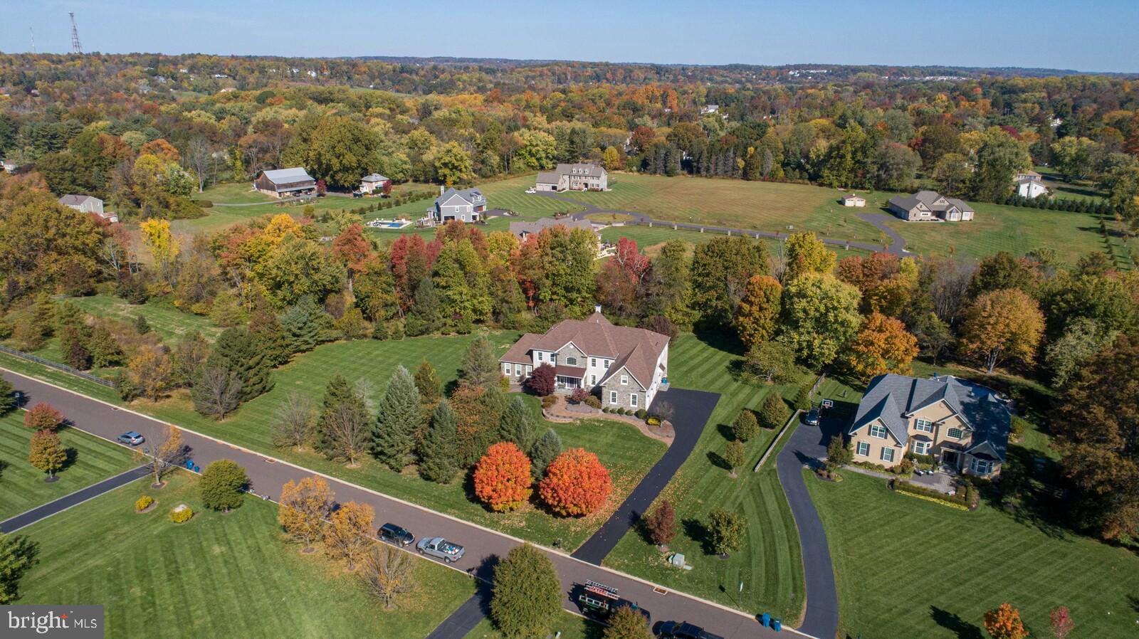 Welcome to 4 Theodore Way, an exceptional Henley model home in highly desirable Doylestown Woods with all the best upgrades to fulfill your wish list! One of only seven homes on a cul-de-sac street, the
setting is idyllic. This home majestically sits back on the lot, with a newly sealed driveway guiding you to the side parking area. As you navigate towards the front door, you will notice the beautifully appointed
exterior materials of Hardie siding and real stone. The bluestone front porch, covered by the portico with mahogany ceiling, is the first of many locations to sit and enjoy your morning coffee. The impressive foyer showcases dual curved wood staircases featuring handsome black metal balusters. Through the foyer awaits the family room, appointed with floor to ceiling stone at the gas fireplace and coffered ceilings with abundant recessed lights. The expanded kitchen features granite countertops, a
huge island with prep sink, copious cabinetry options, a walk-in pantry, stainless steel appliances, impressive oven with 4 gas burners plus griddle with convection feature, additional wall oven, built in microwave, seating areas at island and bar top, and large table space. A butler’s pantry on the way to the generous dining room and a work center are also included in the kitchen area. Extra living space is added by the sunroom, which is attached to the kitchen and features a gas fireplace and walls of windows overlooking a nature enthusiast’s perfect backyard. French doors lead to the deck and large paver patio, both ideal locations for gathering and entertaining, or for quiet personal time. Back in the foyer, there is access to the light filled living room and the expanded conservatory with vaulted ceilings and walls of windows, making it a great space for your game room, playroom, home gym, additional office… the choice is yours! A well-sized office is located at the back of the home too. Completing the
first floor is the mudroom with great storage, the laundry room with sink and egress to the driveway, the three-car garage, and a half bathroom. Upstairs you will find the Bonus Room, a fantastic extra space with unlimited potential and a great closet for second floor storage. The primary suite is enormous and includes a sitting room, large sleeping space, two walk-in closets (one with custom built in cabinetry), and a full bathroom with two vanities, two water closets, a large jetted tub, and a tiled shower with seat and glass door. Three additional en suite bedrooms are large enough to accommodate a bed, dresser, desk and even a couch. The unfinished basement is impressively large and has extra ceiling height, plumbing for a full bathroom, radon remediation system, and walk-up egress via a French door. There are three HVAC systems (first floor, second floor, conservatory) and four thermostats. Other
exceptional upgrades include wood flooring through most of the first floor and at the second-floor landing and hallway, 10ft ceilings on the first floor, 9ft ceilings on the second floor, solid wood doors throughout, extra ceiling moldings and high baseboards, and a propane line directly to the outdoor grill. The lot size of 2.9 acres allows space for everyone to enjoy. This location is connected to walking trails, one of which takes you to the Pine Run Reservoir and an iconic red covered bridge. Award winning Central Bucks School District, just minutes away from charming Doylestown Borough and its many restaurants, museums, and shops, plus access to major highways and public transportation. This one has it all!