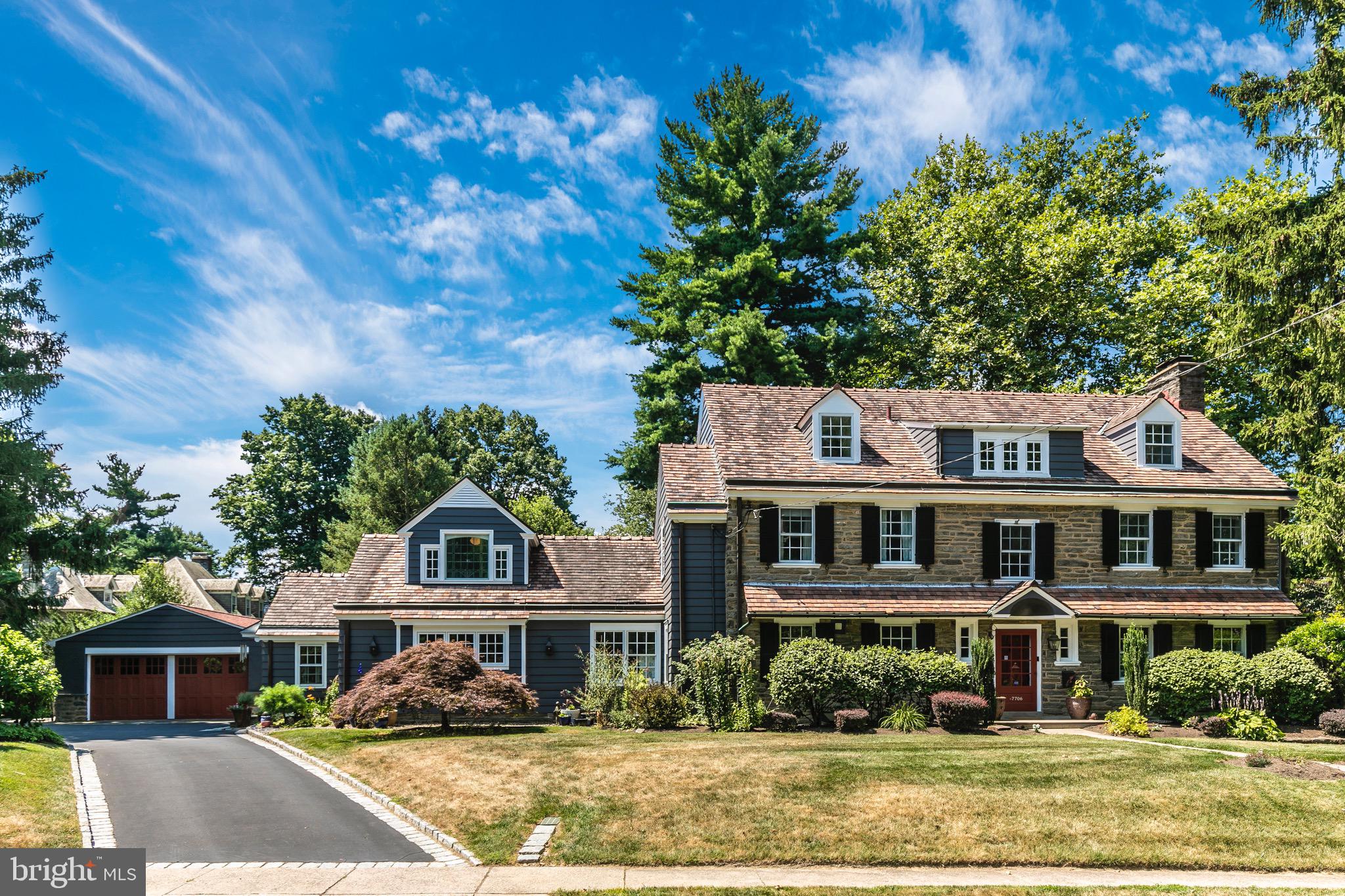 A truly beautiful and favorite Wyndmoor house with a great location. Welcome to 7706 East Lane, a classic 1928 center hall stone colonial in exceptionally great condition on a beautiful lot close to everything. The property is sited slightly above the street allowing for privacy and incredible views of neighboring open green space. Wait until you see an auto enthusiast’s dream of the custom oversized 4 car detached garage – it’s fantastic and looks like a studio – with HVAC, Swisstrax flooring tile, metal workspace/storage cabinets. The owners have loved living at 7706 and it shows by their meticulous care, quality improvements, and system upgrades including zoned heat and central air conditioning. There are appealing home office options while still allowing for desirable living space perfect for both everyday and entertaining. Throughout the interior you’ll find generous scale, fine millwork and flooring details, great closets and storage. An inviting front to back center hall is wide and deep and has the most exquisite stair with wide landings to second and third floors; powder room and coat closet (each with window) flank the front door, wide entry to living room, glass doors to both dining room and sunporch, door to kitchen. The big living room with wood burning fireplace, wall of built-ins, and glass doors to sunporch allows for flexible seating arrangements. Large, gracious dining room with elegant details, door to kitchen for sensible flow. A rebuilt sunporch at the back of the center hall has a stone floor, skylights, many windows, glass door to back yard. Everyone will want to gather in the expansive well designed center island eat-in kitchen with cherry cabinetry, granite counters, tile backsplash with Mercer tile accents, gas cooktop with exhaust hood, 2 wall ovens; incorporating the original butler’s pantry and great back stair. The kitchen is open to a 2 story family room with vintage Rittenhouse Square stained glass window and gas fireplace, captivating loft space with built-in bookcases and long bench, bookcase/secret door to laundry room, tall glass doors to patio to back yard, Right off the kitchen is a big, bright laundry room with 2 windows, counter with sink, many cabinets. A great looking mudroom/back entry hall off the family room has a coat closet, lovely large powder room, and door to driveway. The second floor big primary bedroom has a large custom fitted dressing room with built-ins/center bench cabinet/closet/window. A big, beautiful primary spa-like tile bath has 2 vanity sinks, large stall shower, storage closet. The second and third bedrooms are spacious and have good closets – one bedroom has a door to the loft over the family room which offers space for home office or meditation or perhaps a library. Great looking hall tile bath with shower over tub and vanity sink. Hall door to back stair to kitchen. The third floor has 2 more spacious bedrooms each with closet – one bedroom has door to attic storage room. Hall bathroom has a footed tub with shower, vanity sink, tile floor. The basement is a crisp finished plan of a recreation room with an outside entrance to steps to back yard, workshop room, studio/office with desk and built-ins and fantastic graphic flooring, gym/storage room with wall of recessed storage cabinets, and large pleasant mechanical/storage room. The back yard has room for play and lounging offering patio, green lawn, lovely perimeter plantings, gravel garden with raised vegetable beds, and side English style spiral garden. Township parks, Wyndmoor’s town center with great market and restaurants, major roads, minutes away. More shopping, restaurants, galleries, Woodmere art museum,The Morris Arboretum,The Wissahickon/Fairmount Park, train to center city, close by in Chestnut Hill.