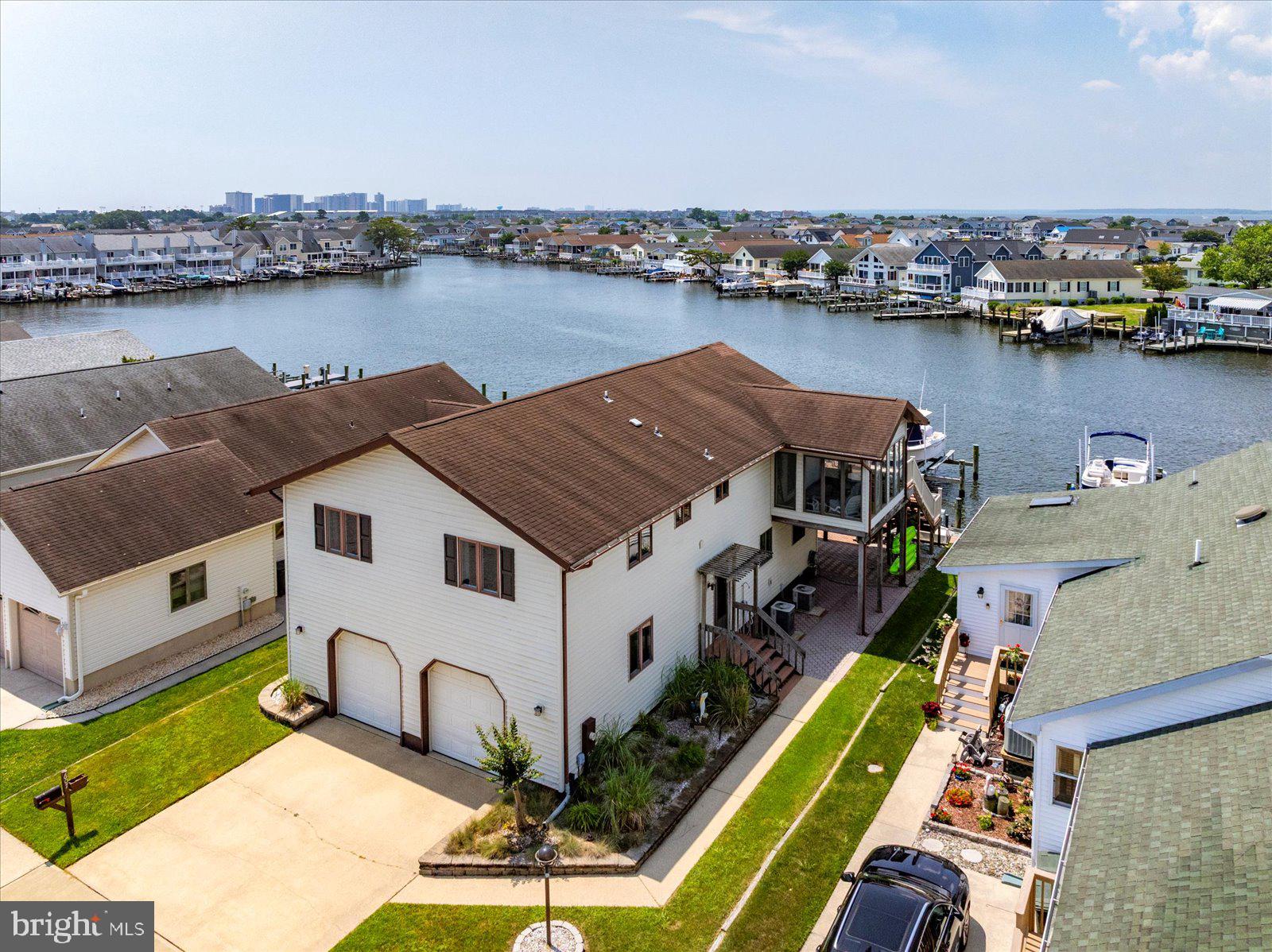 Welcome to your dream coastal retreat! This spacious 4–5-bedroom waterfront home is perfectly situated on a wide canal with expansive bay views in the highly desirable Caine Woods neighborhood of North Ocean City. With two boat lifts, a jet ski lift, and quick access to open water, this property is a boater’s paradise. Inside, you'll find a thoughtfully designed layout ideal for entertaining and relaxed coastal living. The main level features a bright and open family room that flows seamlessly into the waterfront dining area and a large gourmet kitchen with granite countertops and ample cabinetry. Enjoy your morning coffee or evening sunsets from the sunroom or step outside to the large deck—perfect for grilling, crab feasts, and enjoying cool sea breezes. Also on the main floor is the primary suite with en suite bath. Two additional bedrooms and a full bath complete this floor. The lower level includes another bedroom, a full bath with updated shower, a home office (or potential 5th bedroom), and a second spacious family room/game room—ideal for guests or multi-generational living. Additional highlights include a large two-car garage with workshop area, plenty of storage throughout, and a shady paver patio for relaxing afternoons. Whether you're hosting family and friends or soaking in the peaceful water views, this home offers the best of coastal living. Don't miss this rare opportunity—schedule your private tour today before it's gone!