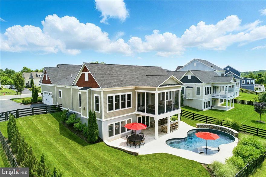 Welcome to a well maintained and beautifully appointed home with backyard oasis and pool. Conveniently located in the heart of the  Willowsford community, this home is situated on a 1/3 acre lot and backs to a conservancy area and mature trees offering serenity and privacy. As you enter the home from the covered front porch, neutral decor and wide plank hardwood floors carry you through the open floorplan. The spacious great room is ready for both entertaining and cozy nights and features a gas fireplace, Hunter Douglas remote control window blinds and custom window treatments. The centerpiece of this home is the handsomely outfitted gourmet kitchen. Highlights include the 14 ft island with space for wrap around seating, cabinetry galore to include glass fronts and pull out drawers, beveled subway tile backsplash, stainless steel appliances to include double wall oven and 5-burner cooktop with hood, both pendant and under counter lighting and a walk-in pantry. The adjoining dining area offers space for a large table and leads to the covered screened in porch, offering more entertaining or relaxing space on this level. Back inside, the main-level primary bedroom suite is generous in size and features a large walk-in closet and spa bath boasting a double head shower with glass door and tile accents and a dual vanity with quartz countertops. Continuing on the main level to what feels like a separate wing of the home, this home offers three additional bedrooms, two full baths and a flexible den area - all main level bedrooms. Additionally, a laundry room, powder room and access to the oversized garage completes this level. The lower level of this home boasts a large recreation room with flexible space to adapt to how you live - whether you want a media area, gaming space or playroom! Additional features include full size windows, an additional full bathroom and walkout to the rear of this home. The unfinished portions of the basement have space for a 5th bedroom (complete with full size window and walk-in closet nook), media room, gym or office. Saving the best for last - the back yard of this home allows you to vacation from home! A 35' freeform shaped saltwater pool is surrounded by sealed travertine patio and pool decking and features a Baja tanning ledge with umbrella hole, customizable lighting, waterfall feature and offers 3.5' shallow end and 7' deep end. To keep the party by the pool, an outdoor kitchen features refrigerator, pizza oven, grill, side burner, built-in trash, storage and paper towel holders, and bar seating. Other features include a fully fenced rear yard with gates, professional landscaping, 8-zone irrigation system, water softener with charcoal filter throughout all faucets in home, and a radon remediation system. NOTE: There is a .25% of sales price assessment paid by buyer at closing to Conservancy.