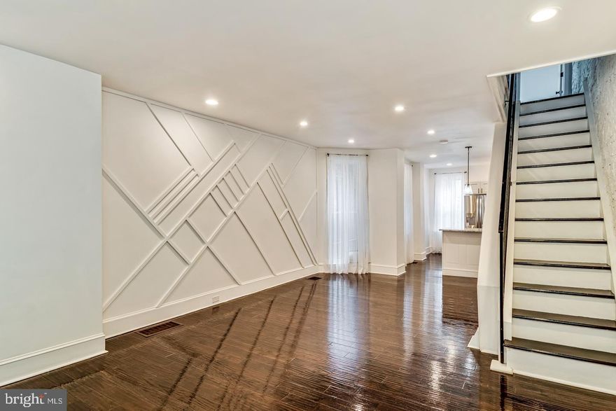 Welcome Home! This  tastefully and stylishly designed  three bedroom home is on a cozy tree lined block in Carroll Park.  Sit on the outdoor porch, and chat with neighbors, or relax watching the world go by. Step inside, and be greeted by authentic wide planked hardwood floors which have been freshly refinished and glisten.  The beautifully contrasting interior is painted bright white, to highlight the natural light streaming through the multiple windows. Notice the loft style exposed brick wall, on one wall, and the geometric, handcrafted herringbone patterned wall feature.  The open concept extends into the high end modern chefs kitchen with extra large granite countertops, great for cooking, plating and hosting. Stainless steel appliances  with gas cooking. Classic subway tile backsplash to complement the wood trim wall in the living space. A rear yard provides enough outdoor space for a bit of grilling and chilling. Upstairs find three bedrooms and a consistent contrasting black and white decor bathroom with floor to ceiling ceramic tile. The home is outfitted with Central Air.  Book your showing as soon as possible!