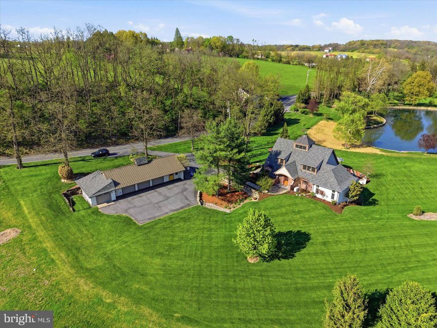 Set across two parcels totaling just about 12 acres, this extraordinary property offers a rare blend of privacy, natural beauty, and thoughtful design. The main parcel features a charming brick cottage-style home on 1.84 acres, while the adjoining 10.22-acre parcel provides potential for an additional residence. Enrolled in Clean and Green, the setting is tranquil, scenic, and rich with wildlife.  

Surrounded by lush gardens and mature landscape, the home welcomes you with a stone walkway and arched transom entry, creating a storybook first impression. Inside the home features custom architecture and thoughtful design finished with the assistance of Brownstone Design. Soaring ceilings, expansive windows, radiant heated floors, and French-imported hardwood floors are found throughout the home. 

The main living area features dramatic two-story ceilings filled with natural light from the walls of windows and hardwood floors- all seamlessly connecting the family room and kitchen. The kitchen is both functional and distinctive, highlighted by reclaimed wood beams from a family barn, curated marble countertops, pendant lighting, double sink, a built-in dining table, and premium appliances including Bosch refrigerator, KitchenAid oven, and JennAir stove top. 

Privately positioned on the main level, the primary suite offers a peaceful retreat with tray ceiling, carpeted floor, window treatments, and access to a private balcony overlooking the backyard and pond. The en-suite bath is beautifully appointed with designer finishes, wall sconces, recessed lighting, a spacious walk-in shower, and an expansive custom closet. A full guest bath on the main level features elegant details including marble accents, hex tile flooring, walk-in subway tile shower, and designer lighting. 

A sunroom just off the main living area provides a cozy yet bright space with a gas fireplace, plank wood ceiling, slate shelf built-in, and panoramic views of the surrounding landscape. A sliding barn door leads to the mudroom/laundry room, complete with custom cabinetry, wainscoting, Speed Queen washer and dryer, storage closet, and side entry access. 

Upstairs, a loft overlooks the main living space and captures stunning views of the property, enhanced by a dramatic cupola with windows. The upper level also includes access to a carpeted attic/crawl space for additional storage. 

The walk-out lower level is expansive and unfinished, offering concrete floors, utility access, and two sets of double doors to the exterior—providing excellent potential for future bedrooms, living space, or recreation areas. 

Outdoor living is truly exceptional, with a slate patio designed for entertaining, complete with retractable awnings, garden space, and peaceful views of the private pond. The pond is stocked and framed by stonework, offering opportunities for kayaking, fishing, or simply enjoying the serene setting. A gazebo, willow trees, and open green space further enhance the landscape. 

Additional features include a converted barn serving as a spacious 4-car garage and workshop with a half bath, ample storage, and multiple access points. With township-owned land bordering two sides, the property offers added privacy and long-term peace of mind. The additional 10.22-acre parcel presents a rare opportunity for future expansion, offering the potential to build a second residence—ideal for a private estate, guest home, or multi-generational living scenario. 

A truly one-of-a-kind retreat where craftsmanship, nature, and tranquility come together.