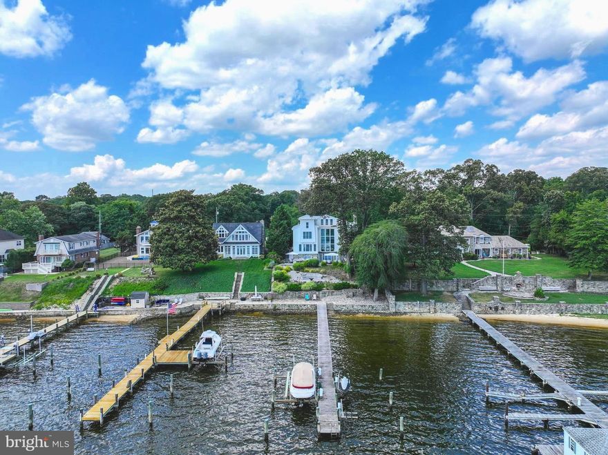 Sellers have just completed extensive improvements to the exterior, to include power washing, painting and trim work, to make this amazing home truly shine! Extraordinary custom built contemporary with sweeping panoramic views of the Magothy River.  Situated on almost 2 acres with 70 feet of water frontage, stacked stone wall and rip-rapped shoreline, pier and boat lift! The private tree lined driveway leads to a detached 2 car designer garage and workshop and allows for plenty of additional parking.  The professionally landscaped/hardscaped front yard adds striking curb appeal and welcomes you in with a wide stone walkway.  When you enter this graceful home, you are met with stunning water views from multiple levels, that are showcased by the thoughtfully curated architecture, without compromising privacy.  Created with superior craftsmanship and elegant details throughout, here form and function have been elevated to the highest level.  The current owners have made extensive improvements over $300,000 to include...front and rear yard landscaping/hardscaping, built-in barbecue, bar, 2 firepits, bespoke outdoor lighting system, replacement of the well pump and both HVAC systems and much more!  You never have to leave home...work from the light-filled loft office space, work out in your home gym or fitness studio and then relax or entertain out on your rear patio and end the day in your top of the line hot tub!  When you do need to venture out, this ideal location has easy access to all commuter routes and is minutes to BWI airport, Baltimore and Annapolis.  LIVE, WORK, PLAY!