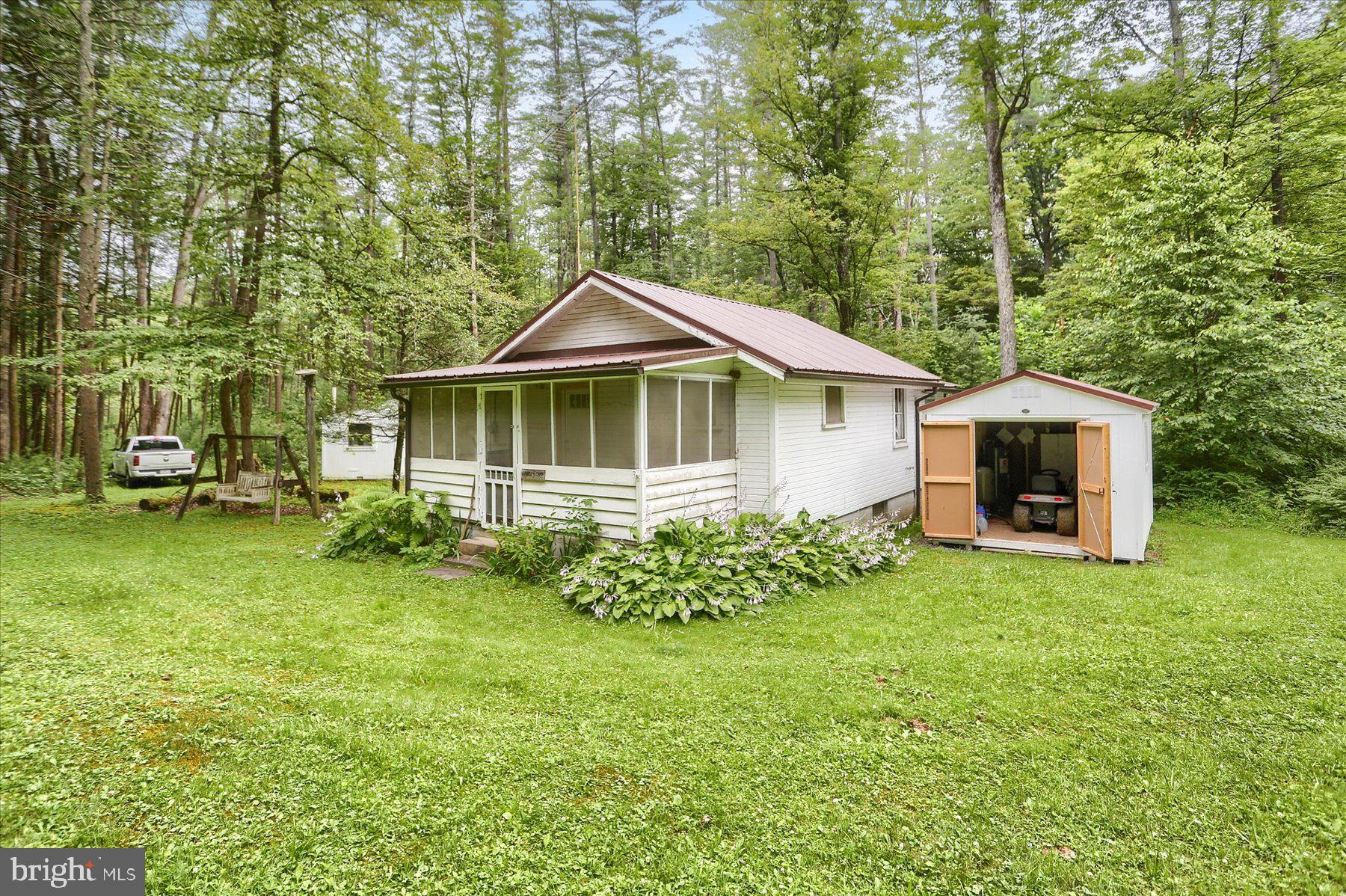 Tucked into Rothrock State Forest and just minutes from Whipple Dam State Park, this charming seasonal camp offers a cozy retreat surrounded by nature. Set on leased DCNR land, the property features two bedrooms, a kitchen area, and a welcoming family room with a newly installed wood insert. Rustic yet comfortable, the cabin is equipped with running water, electricity, and is wired for a landline phone. A classic outhouse and detached storage shed are located just steps from the main structure. Enjoy your morning coffee on the screened-in front porch while listening to the sounds of the forest or enjoy peaceful evenings on the covered back porch. Inside, the vintage charm of the wood-paneled walls and original kitchen cabinetry creates a nostalgic and inviting atmosphere. Whether you're looking for a peaceful place to unplug or a home base for hiking, fishing, and outdoor adventures, this recreational getaway is the perfect spot to relax and recharge in the heart of Central Pennsylvania's natural beauty. The annual lease is $200, and buyers must meet DCNR lease qualifications. The property is not permitted for full-time residence but is accessible year-round. Cabin is being sold as-is and includes furnishings and appliances, making it easy to settle in and start enjoying your time in the woods.