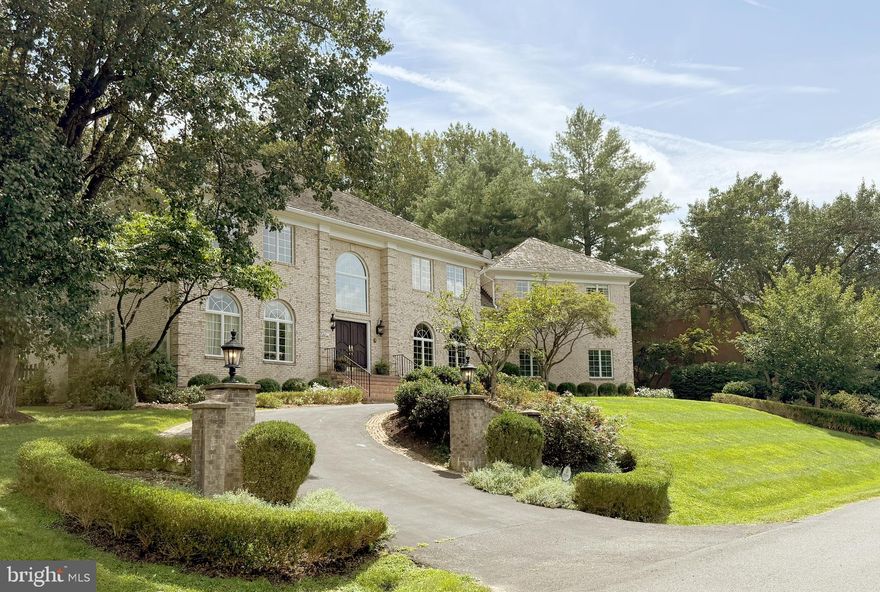 Nestled on nearly a full acre of beautifully landscaped grounds, this exquisite brick colonial offers 7672 square feet of luxurious living space. This is an exceptionally well  built and beautifully maintained home by the original owner, very light and bright. The circular drive is flanked by stately brick pillars with outdoor lighting, and a side-load 3-car garage. The double front doors open to a welcoming 2-story marble foyer with a dramatic central staircase. Elegant panel wainscoting, and gracefully arched doorways mirror the shape of the large, beautiful arched transom windows. Just off the foyer, large wooden double doors open to a handsome library with hardwood floors. Chestnut-colored built-in bookshelves and cabinetry are bathed in natural light from two large, beautiful, arched windows.  Across the foyer, a spacious powder room boasts marble floors and a stunning marble vanity, adding a touch of opulence. The family room features a gorgeous, stone, woodburning fireplace, hardwood floors, recessed lighting, crown moulding. A large glass door opens to the rear patio. The formal living room is exquisite, with soaring 2-story windows, hardwood floors, an elegant fireplace, and charming doorways. The dining room is equally refined, with its own set of arched doorways, hardwood floors, and exquisite mouldings, making it ideal for entertaining in style. The gourmet kitchen is stunning. It features elegant antique white cabinetry including an integrated panel refrigerator. The gas stove is a Dacor with 6 burners. The jet-cut marble mosaic backsplash adds an artistic touch. There is a second oven in the island, plus there is a built-in microwave and trash compactor. Marble countertops and diagonally laid marble floor tiles harmonize beautifully with the cabinetry. The sunny breakfast area features a vaulted cathedral ceiling and 2 skylights. A large window and a large cozy window seat overlook the back yard. An arched window lets more light onto the upper level. An additional staircase leads from the kitchen area to the primary bedroom.  Connecting the kitchen to the garage is a convenient mud room/laundry room with a pantry closet, new GE Profile washer and dryer, a sink, and ample cabinetry. The sun room features hardwood floors, a cathedral ceiling, 2 skylights, and a marble fireplace between built-in cabinetry and shelving. A large glass door leads to the expansive rear patio, perfect for enjoying the serene surroundings. The upper level has hardwood flooring throughout, featuring the primary suite plus four additional generously sized bedrooms, a jack-and-jill bath with a double vanity and water closet, a hall bath, and a sitting area. The bathrooms feature elegant wallpaper, stylish light fixtures, and a skylight in the hall bath. The enormous primary bedroom features a dramatic cove ceiling and a walk-in closet with custom shelving. A luxurious en-suite bathroom with a double vanity, a bidet, and jetted corner tub with picturesque windows. The lower level is quite large and completely finished, with neutral wall to wall carpeting, neutral walls, and recessed lighting. There is a rec room, game room, den/potential 6th bedroom, a full bath with a bidet, and utility rooms. In the rec room there is a fireplace flanked by built-in mirrored shelving, a granite wet bar with a mini fridge, and a wine room. The expansive treed back yard offers privacy and relaxing views, perfect for a pool. The giant 1400+ sq .ft. Flagstone patio wraps around and is accessible from multiple rooms on the main level. This fabulous patio is particularly picturesque and perfect for parties. The spacious garage features a built-in refrigerator, built-in storage cabinets, and automatic door openers. There is an indoor-outdoor intercom system that conveys as-is. Located on quiet cul de sac of 20 estate homes, with convenient access to Tysons, DC, Reagan National Airport, Dulles, Silver Line Metro, Great Falls Park, and Langley Schools.