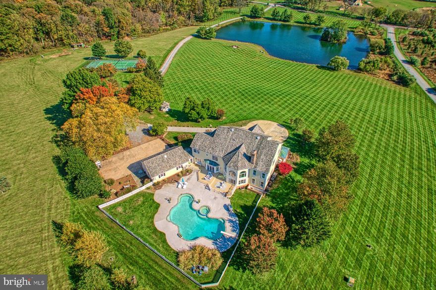 Imagine the feeling as you leave the world behind and drive onto your private country retreat. A 4 acre stocked pond, welcoming wrap around front porch, and scenic views provide the setting for this lovely estate home on 37-plus acres comprised of two lots.  The home is anchored by all of the amenities you would expect in a home of this caliber.  A two-story family room with a wood-burning fireplace, a large well-appointed kitchen, butler's pantry, library, office, formal living and dining areas as well as two half baths are found on the main floor. The upper level consists of a primary suite with a cozy sitting room, large private bath and two walk in closets.  Three generously sized additional bedrooms, and two full baths round out the second floor.  The lower level 's entertaining area includes a wood-burning fireplace, private room used as a 5th bedroom, full bath and large storage options.   Outside you will find room to entertain with a pool/spa, outdoor fireplace and large patio.  Enjoy watching tennis matches on the lighted court from the observation deck that also enjoys scenic pond views.  Kids both young and old will enjoy taking a canoe or boat to your private island on the pond.   With close proximity to commuter routes, minutes to downtown Leesburg and all Loudoun County has to offer, this home is close to everything and yet a world away.