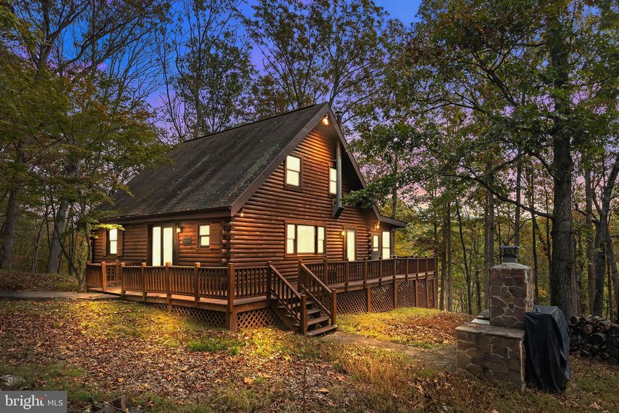 Nestled deep within the gated community of The Crossings at the Great Cacapon, this true log home offers the ultimate private retreat—just over two hours from DC. Scandinavian-inspired and mountain-sophisticated, it’s sold fully furnished and turnkey, ready for your next getaway or second home. Enjoy beautiful acoustics with the conveying stereo and speaker system.
The updated kitchen blends clean design with modern convenience, and the upper loft bedroom features a Sleep Number bed for personalized comfort. Meticulously maintained, the home boasts fresh exterior staining, an upgraded electrical panel, new baseboard heaters, relocated water system to a temperate space, and careful upkeep against woodland pests.
Enjoy the wraparound porch for outdoor dining or relaxing in total seclusion, and the 3-season sunroom for morning coffee, afternoon reading, or cozy movie nights. Set at the end of a quiet cul-de-sac, you’ll never see a passing headlight—only forest, mountain views, and starry skies. The property also includes a picnic area, fire pit, and wood grill.
Residents enjoy fiber optic internet, ideal for remote work or streaming, along with three private river access points for kayaking, fishing, and swimming in the Cacapon River. With no short-term rentals allowed, the community maintains a peaceful, owner-occupied atmosphere.
A fairytale escape where modern comfort meets mountain serenity.