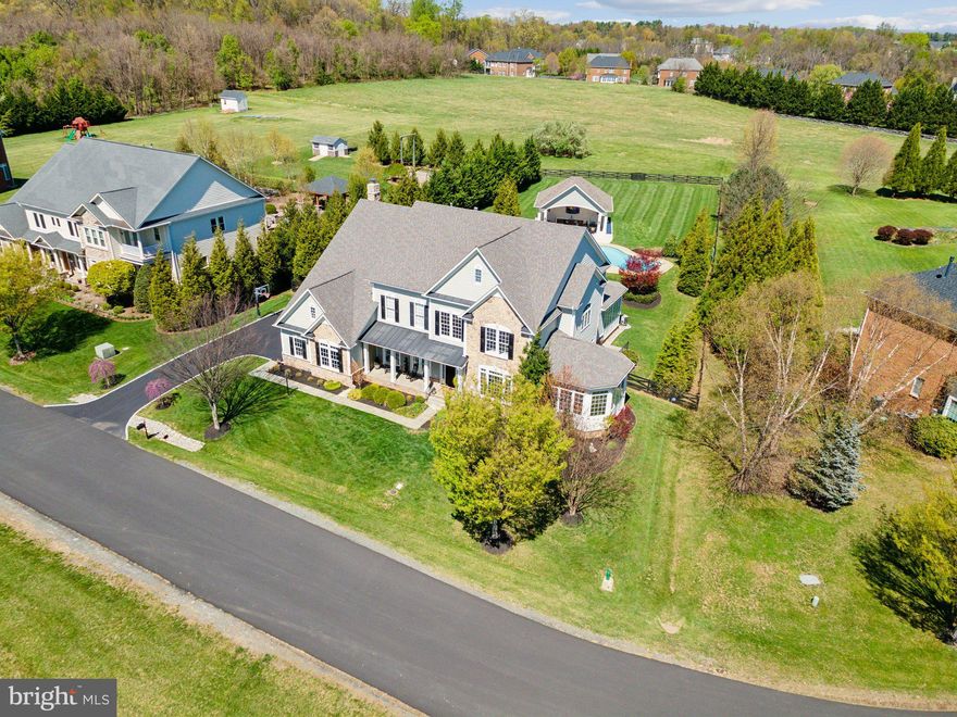 All offers due Saturday (04/26) by 3:00PM. Welcome to an exceptional estate offering over 9,000 square feet of luxurious, turn-key living in a secluded reserve community just minutes from historic downtown Leesburg and 30 miles from Washington, D.C. Situated on a private cul-de-sac within a tranquil wildlife preserve, this meticulously maintained residence features five spacious bedrooms, seven bathrooms, and a resort-style backyard, blending refined design with practical comfort throughout.

Upon entry, a grand two-story foyer sets the tone with wide-plank white French oak flooring, designer lighting, and a sweeping curved staircase. The main level is thoughtfully configured for both formal entertaining and everyday living. Formal living and dining rooms include statement light fixtures and remote-controlled window treatments. The completely renovated gourmet kitchen is equipped with marble countertops, stainless steel appliances (2025), a large center island with counter seating, walk-in pantry, and a sunlit breakfast room. An expansive family room offers a gas fireplace, wet bar, wine fridge, and French door access to multiple outdoor patios. A private office and an adjacent library—each enclosed with glass doors—are finished with built-in cabinetry and automated window treatments. A mudroom entry from the three-car garage provides three oversized closets, offering generous storage.

The upper level, accessible by both front and rear staircases, includes four well-appointed bedroom suites, each with a private full bath and custom walk-in closets. The Owner’s Suite serves as a private retreat, complete with a sitting area, wet bar with wine fridge, and remote-controlled lighting and shades. The recently renovated spa bathroom features marble slab walls, dual vanities, a soaking tub, floor-mounted fixtures, a frameless glass shower with triple shower heads, and a dedicated glam vanity. A generous boutique-style walk-in closet offers two distinct sections, custom drawer systems and valet features. A spacious laundry room with washer and dryer completes the upper level.

Designed with hosting and wellness in mind, the fully finished lower level includes two expansive lounge areas, a full-service bar with refrigerator, and a billiards space. A private home gym—conveying with treadmill, elliptical, rower, squat rack, free weights, and additional equipment—sits alongside a large guest bedroom with full bath and custom closets. Three additional storage rooms, each with built-in shelving, provide functional convenience.

The landscaped backyard is a true outdoor oasis, featuring a 2-foot to 9-foot deep heated saltwater pool with an adjoining spa, surrounded by multiple stone patios and lounging areas with integrated hardwired lighting. The architect-designed, fully equipped Pool House includes a powder room, two refrigerators, wine fridge, icemaker, sink, custom cabinetry, a finished storage room, overhead heaters, a 9-foot ceiling fan, overhead lighting, and a 80-inch outdoor television. An outdoor kitchen and grill system enables seamless alfresco dining, while a gas fire table and covered front porch provide year-round enjoyment. Additional outdoor amenities include a basketball net, in-ground irrigation system, estate-style fencing, and a system of exterior lighting along walkways, the driveway, and throughout the pool area.

Recent upgrades include HVAC systems (2023), stainless appliances (2025), pool heater and pump (2024), pool motor and temperature sensor (2025), driveway pavers and river rock hardscaping (2024), new exterior doors (2023), French drains, and custom closets by Closets by Design. The home also features estate-sized chandeliers, tinted windows, and remote-controlled blinds throughout.

Located within a quiet reserve featuring scenic nature trails, and zoned for top-tenured Loudoun County schools (Simpson Middle School and Loudoun County High School).