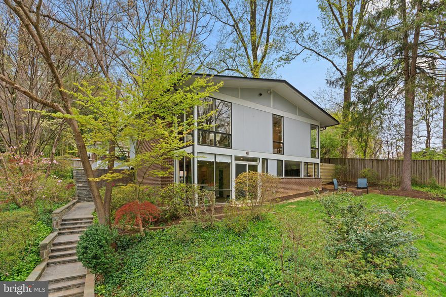 Discover this stunning Mid-Century Modern home by the iconic Charles Goodman, expertly updated for modern living. Featuring 3 bedrooms, 3 full baths, and 2 cozy fireplaces, this home blends timeless design with contemporary amenities. With custom high-end kitchen and bath renovations, gleaming hardwood floors, and a fully finished lower level, it offers the ultimate in style and comfort.

Nestled in the serene Rock Creek Woods neighborhood, renowned for its cherry tree-lined streets and unique Goodman homes, this residence showcases an open floor plan, exposed wood-frame details, and large windows that flood the space with natural light—perfect for enjoying the surrounding beauty.

The main level includes a custom kitchen with sleek finishes, a spacious living room with a wood-burning fireplace, and panoramic tree-top views. Two bedrooms and two renovated bathrooms complete this floor, which also opens to a private patio in the fenced backyard. The lower level offers additional living space with a second fireplace, another family/recreation room, a large bedroom, a full bathroom and a laundry room with ample storage.

Conveniently located near Rock Creek Trail, parks, tennis courts, and playgrounds, this home is also minutes from Walter Reed Medical Center, NIH, downtown Bethesda, and major shopping centers like Pike & Rose, Whole Foods, Safeway, and Costco. With easy access to Grosvenor and Wheaton Metro stations and major highways (I-495 and I-270), this home offers both tranquility and convenience. Don't miss the opportunity to live in this architectural gem in one of the area's most sought-after neighborhoods!