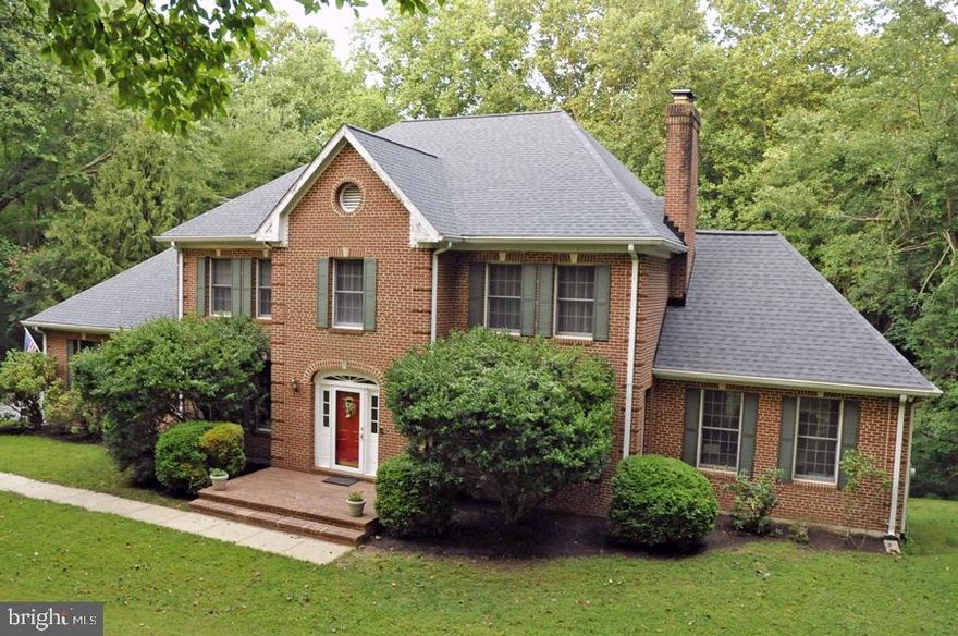 Three level, traditional all brick center foyer colonial in 5 acre wooded setting on rustic road. Custom built & occupied by same owner since construction. Five/six bedroom with four full bathrooms. Two, dual zoned, programmable Trane heat/AC pump systems. Well water treatment system, including water  softener, PH neutralizer, and Trojan UV Max modules. Four fireplaces with brass / glass enclosures. Two 2 car garages (main & lower levels). Insulated vinyl clad wood windows. Dedicated lower level laundry room with ample cabinet space. Main level mudroom is also plumbed & wired for washer/dryer installation. Hard-wired security system with monitoring. Oversized gutters and downspouts. Ten foot ceilings in lower level, nine foot ceilings w/crown molding & hallway picture frame moldings on main level, eight foot ceilings on upper level. Upper Level – Master suite with bathroom marble floor/tub enclosure, soaking tub with whirlpool jets as well as glass shower enclosure, and ceiling heat lamps. Adjoining room useable as either fourth upstairs bedroom or nursery / sewing / sitting room. Master suite has large walk-in closet as well as cedar lined walk-in closet. Two other bedrooms on upper level as well as a full bathroom with traditional tub/shower and ceiling heat lamps. Main Level – Large foyer w/2 closets, front facing living room and dining room, kitchen with convection wall oven & microwave in addition to standard stove, large family room, eat in area between kitchen & family room, side server/bar between kitchen & dining room, walk-in butler’s pantry, bedroom or study with walk-in closet, bathroom, deck, and large
sunny den with ample windows and Casablanca fans. Two car garage. Lower Level (walk out) – Large laundry room, very large studio / entertainment / game room with fireplace & ample closet space, bedroom, workshop & equipment room, and full bathroom. Two car garage. Original house plans will be available to buyer @ closing. Four rooms on main level have had recent light office use as owner winds
down professional practice.  Major, warranted, roof replacement in May 2023