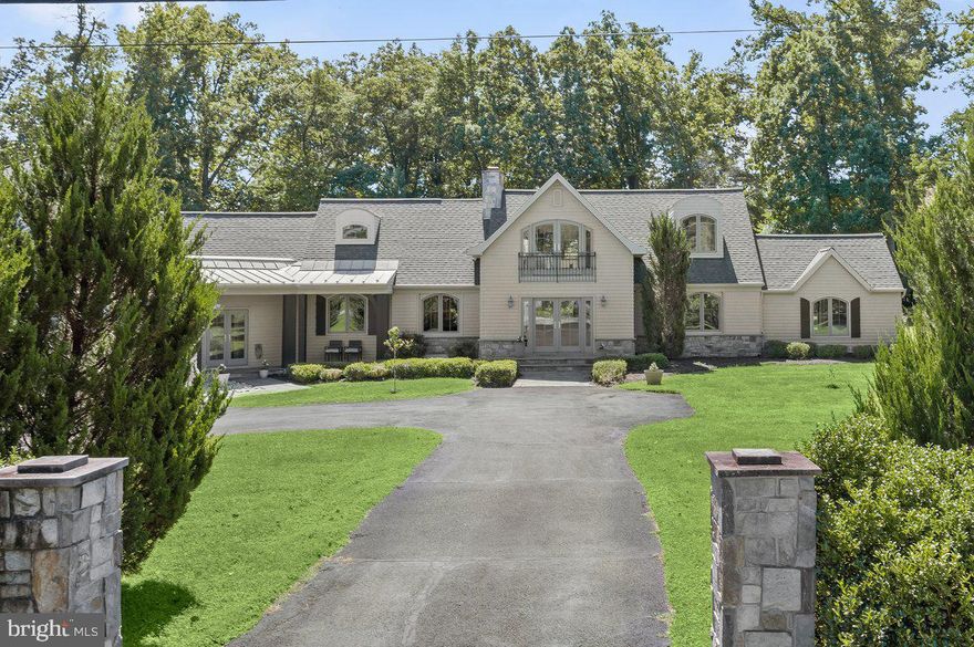 Artfully renovated, upgraded and expanded by Transforming Architecture and CGC Builders in 2013, 9820 Newhall Road is a stunningly crafted residence boasting modern amenities, chic interiors and incredible scale throughout 3,378 beautifully curated square feet. Prominently perched on just over an acre of level and lush land, this transitional Colonial lends the ultimate suburban oasis while enjoying the convenience of close proximity to Potomac’s shopping, dining and entertainment destinations. Notable updates and upgrades during the home’s extensive 2013 recreation include all new Anderson Windows, roof replacement, professional landscaping, and handsomely engineered hardwood flooring throughout the home’s Main Level. With no detail left untouched, this exquisite residence is exemplary of one-level living at its finest.
Along the slate entry pathway from the stone pillar entrance, Glass French doors open to offer a warm welcome to the light-filled home’s open concept interiors. The interior’s sprawling Living and Dining spaces are separated by a two-sided, free-standing stone gas fireplace to provide a distinct yet seamless transition between the two gathering spaces. Dramatic Cathedral ceilings with wood accent beams are on display in the Dining and Family Rooms, highlighting the home’s breathtaking scale and flawlessly executed open layout. Walls of windows illuminate the Family Room and provide magnificent vistas of the level, one acre lot that surrounds. Open to the Dining and Family Rooms, the expansive Gourmet Kitchen is sure to thrill any caliber cook or avid host. Complete with Kitchen Aid Stainless Steel appliances, an oversized island with breakfast bar seating, granite countertops, a coffee bar, and abundant storage, this Kitchen is truly the heart of the home. With French Doors in both the Family Room and Kitchen, outdoor entertaining and dining on the screened porch or rear patio is just steps away. The Primary Suite Wing is privately appointed off the Main Level to provide a discreet oasis within the residence. Through double entry doors, the sprawling Primary Suite opens to a Sitting Room/Office Nook leading to the expansive Bedroom complete with cathedral ceilings. The ensuite Spa Bathroom is a relaxing haven, featuring an oversized stall shower, soaking tub, dual vanity with polished Travertine counters and access to both the rear patio, laundry facilities and a fully outfitted walk-in closet. Complete with an office featuring a gas fireplace and skylight, a Powder Room, and a mud entry with direct access to the 2-car Attached Garage and covered front Porch, there is everything to love about this Main Level paradise! 
The Upper Level features the principal guest rooms and includes two Bedrooms and full Bathroom, with space for a potential fourth bedroom above the garage. An unfinished Basement is accessible from the exterior and offers ample storage space, along with the utility systems.