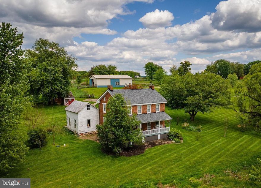 Your dream of a functional farmette on over 10 acres with classic brick farmhouse in Carroll County can be realized at 2100 Blacks Schoolhouse Road.. Warm, inviting, and with all main systems and roof completely recently updated, you'll enjoy all modern conveniences combined with the charm of yesteryear - but without the worry! The wonderful back porch takes you inside the main level, which features hardwood floors, newer appliances, an open country-style eat-in kitchen with wood stove, and plenty of room for a large table. A separate formal dining room provides flexibility for a first-floor office or playroom if preferred, while the adjacent living room is just off the kitchen. A half bath with washer/dryer and plumbing in place for a shower complete the first floor. With laundry also able to be relocated upstairs, the space provides plenty of opportunity for a second full bath or keep as-is! Upstairs,find three spacious bedrooms with wonderful natural light, a very large updated full bath with tub/shower combo, and walk-up access to the attic for additional storage. The house is painted in a neutral palette throughout and is just one of those cozy, inviting spaces you can't help but feel "at home" in. There is also a large summer kitchen attached under the porch that would serve wonderfully continued to be used as storage or renovated into additional living space - a primary suite, family room, office, or even attached garage! Outside, find multiple fenced pastures and a large, center-aisle barn with space for at least 4 stalls, equipment parking, water and electric, ready for your animals, homesteading accessories, parking - whatever you need! The topography is gently rolling with plenty of flat, usable acreage and the pasture is plentiful! Additional outbuildings include a shed and chicken coop, all in a pastoral setting with room to expand your vision - gardens, animals, equipment, future improvements, or simply open space to enjoy. Whether you dream of bringing horses home, starting a hobby farm, or settling into a slower lifestyle with room to roam, this 10-acre farmette is the perfect setting to plan your future chapters. Quiet, functional, and full of possibility - come explore the potential!