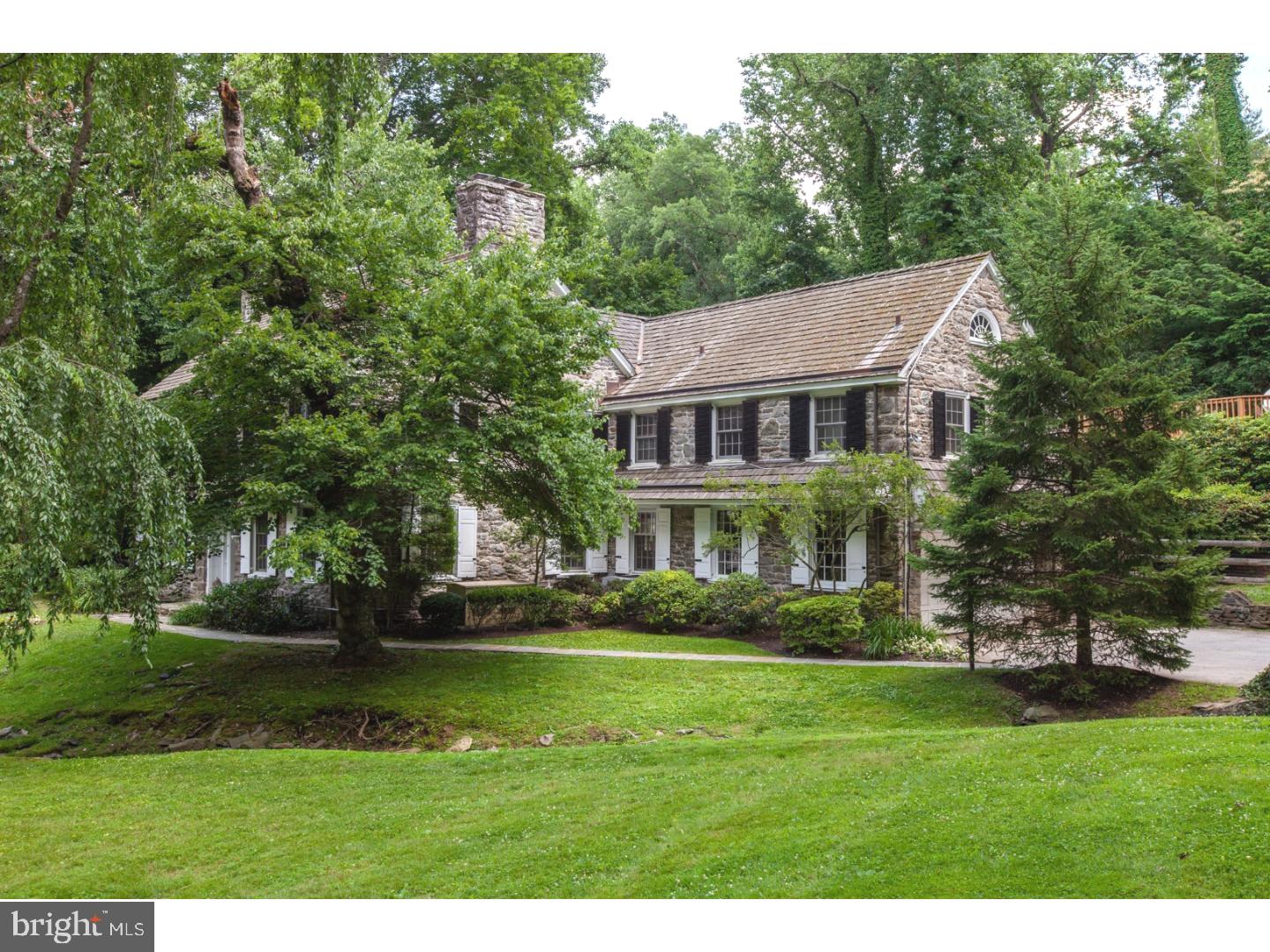 Quick Settlement Possible. Welcome Home! Charm & character abound in this stately three story Stone Colonial Home in the Penn Valley Neighborhood of Lower Merion. Situated on a picturesque 1.5 acre lot with public water & public sewer you get the best of both worlds with the feel of living in the country, but the convenience of shopping, restaurants & transportation nearby. With easy access to major interstates & highways, it's less than 30 minutes to Airport, Center City, King of Prussia & Valley Forge. First Level: Flagstone walkway to the covered entry featuring extra wide front door with two side lights, center hall extends the width of the home with access to large coat closet, powder room and exit to rear flagstone patio, formal living room with wood trimmed brick fireplace, chair rail, crown molding, and two sets of French doors to spacious side yard and rear patio, formal dining room with brick gas log fireplace, built-in scalloped hutch, chair rail, crown molding & deep sill windows, fabulous gourmet kitchen with wood cabinets - floor and ceiling, granite counters, Sub Zero refrigerator, dishwasher, garbage disposal, trash compactor, 6 burner gas cook-top, Viking oven, built-in microwave and extra wall oven, spacious breakfast room with exits to rear patio & attached two car garage, office area / Butler's Pantry, mudroom with coat closet & outside exit. Second Level: Wide staircase with Palladian arch window at landing with hallway leading to Master bedroom with fireplace, two closets & master bath, 3 additional bedrooms, Office/Study/Home Gyms, laundry room, tiled hall bath and storage area. Third Level: Two large bedrooms, skylights, cedar closet, full bath & ample closets for storage. Lower level: Two entrances to finished recreation room with over-sized fireplace, powder room, large unfinished area has utilities, former photography room/potential wine cellar & storage. Rear yard features in-ground heated pool with Hot Tub & huge wrap around deck, natural gas grill line, professional landscaping with mature trees, shrubs & perennial flower beds. Side yard has enclosed play area & front yard has stone bridge & private wooden bridge over stream. Beautiful random width pegged hardwood floors on first floor, refinished hardwood throughout remainder of home, unique wood trimmed windows with deep sills, front & rear stairways to second floor & lower level, 4 fireplaces, neutral colors & tasteful decor throughout. Possibilities are endless as you will see when you tour this exquisite home. Ideal home for Au Pair.