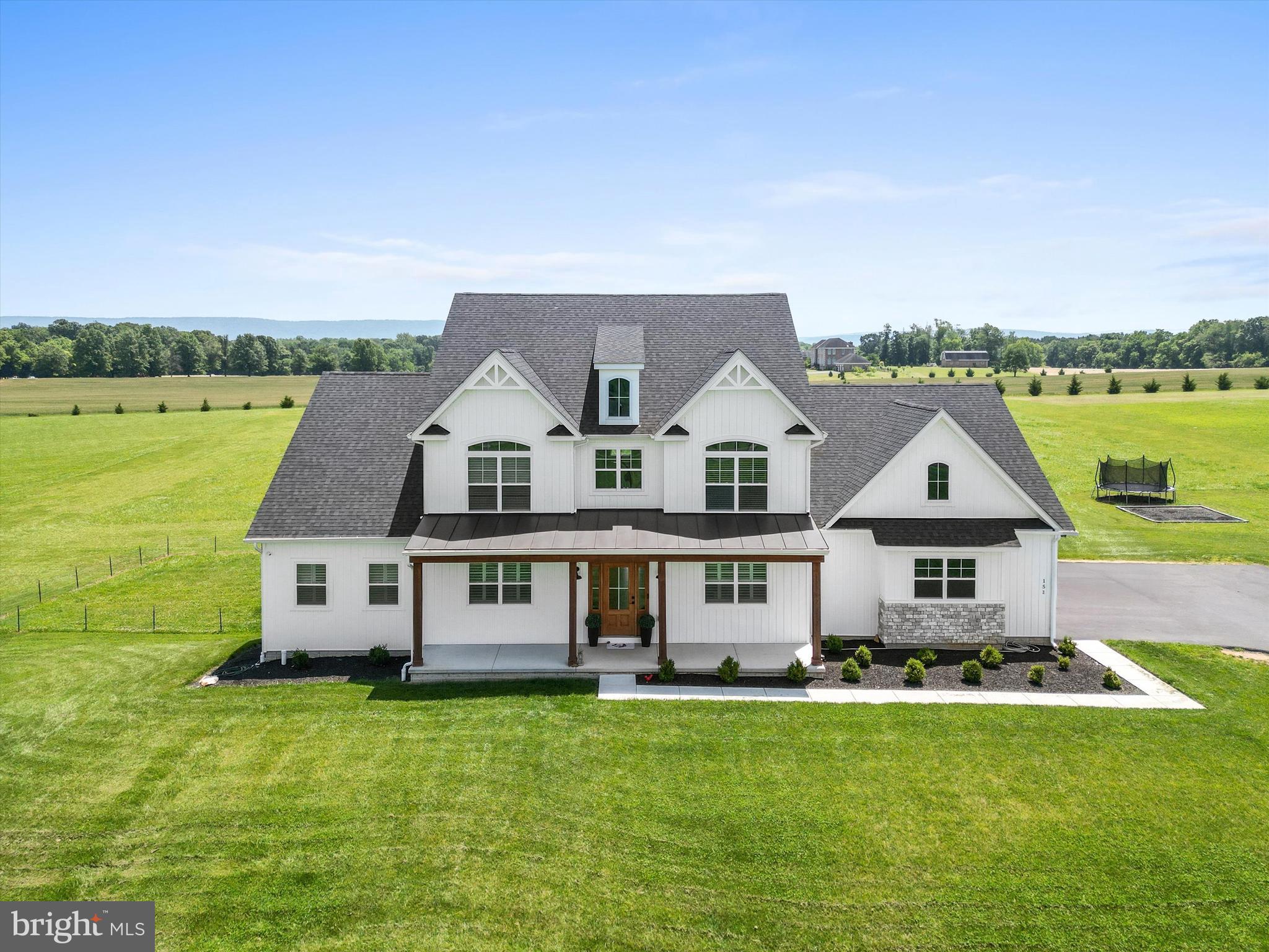 Price Reduced!!! Welcome to 151 Summerfield Way, a stunning 2022 home on 5 peaceful acres outside of Shepherdstown, WV. Built in 2022, this property offers the perfect blend of luxury finishes, thoughtful design, and functional space — ideal for both everyday living and entertaining. Every detail of the house has been thoughtfully designed, featuring custom window treatments, wainscoting, exposed beams, crown molding, custom built-ins, and gorgeous hardwood floors throughout.
Step into the soaring two-story living room, anchored by a dramatic floor-to-ceiling stone fireplace, exposed wood beams, and French doors that walk out to your covered back porch with fireplace. The open-concept layout flows into a gourmet kitchen featuring quartz countertops, top of the line appliances, premium cabinetry, a large pantry, breakfast bar with seating, and a large island perfect for gathering. The main-level primary suite offers a true retreat, featuring custom wainscoting, a brick accent wall, and exposed wood beams. It includes a spa-like bath with a soaking tub, separate shower, dual vanities, and walk-in closets. The main level of this extraordinary home also includes an additional living room or home office, a mudroom, and a half bath.
Upstairs you’ll find four spacious bedrooms, including a second primary suite, plus two full baths — offering flexible space for family, guests, or work-from-home needs.
Enjoy quiet evenings on the covered back porch with a cozy propane fireplace, or take in the sweeping views of the flat, fully usable lot that backs to open farmland. With a 3-car garage, an enormous dedicated laundry room, and an expansive unfinished walk-out basement ready for your vision, this home truly has it all. The whole house generator, alarm system, and cameras are even included for peace of mind!
Tucked into a small cul-de-sac neighborhood with no active HOA and only light restrictions, this is your opportunity to enjoy 5 acres of modern country living — without sacrificing comfort or convenience. Also located just 5 minutes from the Marc Train Station for DC commuters and within minutes from major driving commuter routes Rte. 340 heading into MD and Rte. 9 heading into VA.
