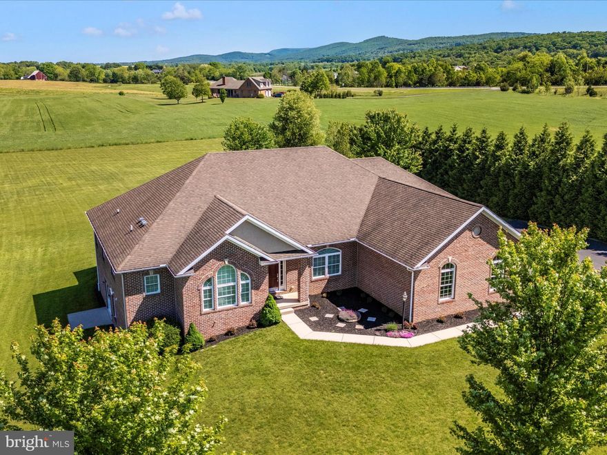 This home offers a delightfully modern twist to main-level living.   Stunning custom-built rancher with tons of space and scenic views in every direction!   Situated on over 3.5 acres and just up the road from Big Cork Winery!  All brick exterior with a three-car side load garage, coupled with over 3,300 finished square feet on the main level.  Beautifully appointed with 9 ft & vaulted ceilings, wood floors,  a central vacuum, and custom plantation shutters.  The gourmet kitchen is perfect for the pickiest of cooks and includes GE Monogram appliances, two sinks, and a spacious island.  The large covered rear porch (just off the kitchen) is perfect for enjoying the scenic pasture, sunsets, and mountain views.  FOUR large bedrooms with a full bath attached to each.  The primary bedroom with ensuite includes a large jacuzzi jet soaking tub and two walk-in closets.  No detail was missed.  This very functional floor plan includes a main-level laundry/mud room.  There is even room to grow in the walk-out level basement (with 9 ft ceilings too!) that is ready for your personal touches.  A fully finished bath on the lower level is all ready for you to enjoy.  Heat is an electric heat pump with propane gas backup to keep you toasty when the temperatures drop. Tranquility at its finest.  Model home condition.  Nothing left to do but move right in and make it yours!