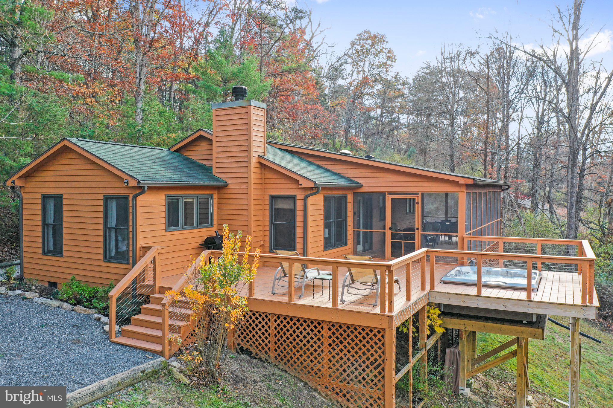 Meticulously maintained 2 bedroom, 2 bathroom architecturally designed cabin on 7+ acres. This home features an open-concept floor plan with beautiful vaulted ceilings and rustic wood-framed beams, thoughtfully laid out with a wood-burning fireplace that can be enjoyed from the living room, dining room, and kitchen. The fireplace features a reclaimed wood mantel and a natural stone hearth. There are hardwood floors throughout the entire cabin, the primary bedroom features tremendous natural light, an ensuite bathroom (updated 2023), and a walk-in closet. The second bedroom features a vaulted ceiling clad in tongue & groove pine and evokes a tremendous sense of coziness. The adjacent full bathroom features a beautiful porcelain tile shower (updated 2018). This home features truly open-concept living; the kitchen features a large island and upgraded premium, high-end Kitchenaid appliances. The dining room and living room are perfect for indoor entertaining. The large screened-in porch doubles as an outdoor dining room and outdoor living room while enjoying beautiful mountaintop views. Just outside the screened porch, a large sunny deck with a sunken-in premium Hot Springs Flash 7-person hot tub (added in 2021) creates the perfect mountain escape. The home features a premium Whirlpool washer & dryer, central heat, and air conditioning and is offered furnished, making it completely turnkey. The exterior of the cabin and decks were stained in 2022. Located just two hours from the Washington, D.C. Metro area in the heart of the sought-after Lost River community, this property is served by high-speed fiber optic internet and all underground utilities. Conveniently located less than a mile from the Guesthouse Lost River, featuring entertainment and fine dining, and within a few miles of nearby shopping, local markets, & community businesses. The Lost River State Park and George Washington National Forest, also just a few miles away, feature thousands of acres of hiking trails, horseback riding, and more. CLICK on the camera icon for a 3D Virtual Tour