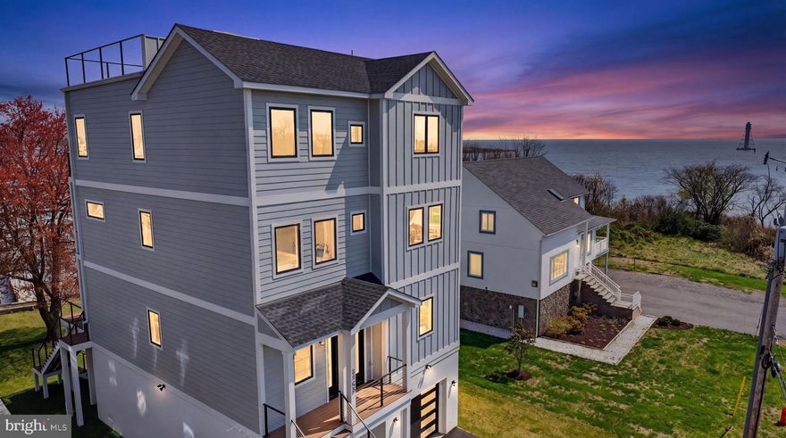 Introducing an extraordinary ultra-luxury waterfront new construction on Miller��s Island, where cutting-edge design meets effortless coastal living. Spanning over 4,000 square feet across four impeccably finished levels, this one-of-a-kind residence offers 4 bedrooms, 3.5 baths, elevator and panoramic views of the Chesapeake Bay from nearly every vantage point.

Built with uncompromising quality and innovation, the home features 600-amp electrical service, dual-zone HVAC with high-efficiency inverter condensers, whole-house humidification, and full spray foam insulation for superior comfort and energy performance. Striking architectural elements include 11-foot ceilings, 9-foot doors, and premium Marvin Windows that flood the home with natural light, all wrapped in durable Hardie Plank siding.

At the heart of the home, a designer chef’s kitchen showcases custom cabinetry, a statement hood, a 36-inch induction cooktop, commercial-grade stainless steel appliances, speed oven, and an oversized quartz island with dramatic full-height quartz walls—perfect for entertaining at scale.  Open floor plan on main level with wet bar and 76” Modern Flames fireplace. Dual sets of 3 panel sliders open to rear tree deck with cable rails for unbelievable views.

Curated for both relaxation and entertainment, the residence includes a private in-home theater experience in the primary suite featuring a projection system with Dolby 5.1 surround sound, along with pre-wired audio throughout. The primary suite is a true retreat, offering a custom accent wall with sconces, retractable projection screen, dual walk-in closets, and a spa-inspired bath with radiant heated floors, frameless glass shower, bidet, and refined designer finishes.

The upper levels continue to impress with spacious secondary bedrooms, a beautifully appointed en-suite, and a convenient laundry room. A top-floor loft with wet bar seamlessly opens to a private deck, creating an ideal indoor-outdoor entertaining space.

The crown jewel: an expansive rooftop deck complete with Duradek and hot tub, delivering breathtaking 360-degree water views—an unrivaled setting for sunset gatherings over the bay.

Additional luxury amenities include EV charging station in 1 car garage, finished lower walk out level, freshly sodded yard, new pier with floating jet ski/kayak dock, integrated security system, whole house generator pre-wired, and smart-home readiness throughout.  

A rare opportunity to own a true waterfront masterpiece where modern luxury, technology, and coastal elegance converge.