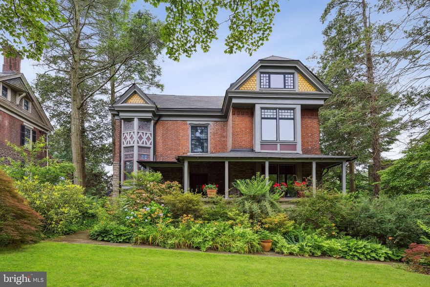 Thoughtfully renovated by a designer for personal use, this Queen Anne residence with carriage house and incredible grounds is the quintessential Mount Airy dream home. Suited for 21st-century living while remaining in perfect harmony with its original character, the property features meticulous updates to the kitchen and bathrooms alongside new mechanicals, plus details like a combination of original oak parquet, salvaged oak laid on the diagonal, and original pine flooring; custom replacement period-appropriate Andersen windows; and woodwork restored or custom milled to match the original throughout the interior and exterior. The detached Wissahickon Schist stone garage and carriage house provides not just parking but a workshop area and a flexible second-floor space for a three-season home office, artist studio, yoga room, or other private retreat. Outdoor living is a dream, with two porches overlooking the grounds–a large front and back yard with mature landscaping, pond and waterfall. Inside the house a grand entry foyer, in line with the home’s generous proportions, is at the center of the first floor; its gorgeous and slightly whimsical wallpaper sets the tone for a casually elegant sensibility throughout. Dramatic landings with original leaded glass windows separate each floor. Five bedrooms and two baths, including a serene primary suite consisting of an expansive bedroom with a dressing room ringed by a pair of closets, WC and well-appointed bath, plus a conveniently placed laundry closet and a cedar closet are spread across the two upper floors. There’s architectural interest throughout, including curved plaster nooks, deep window seats with original millwork and cozy alcoves created by dormer windows. The living room with coffered ceilings and original double doors to the rear porch is anchored by the woodburning fireplace with limestone mantel. The kitchen is quietly sophisticated, with sleek and functional white Ultracraft cabinetry with Emtek ring pulls, including two floor-to-ceiling pantries flanking the fridge, white subway tile backsplash with wall-mounted gooseneck faucet, Caesarstone counters and a Bertrazonni range. Restoration work was all inclusive, from the removal and refurbishing of all interior hardware to all new roof surfaces, plumbing, wiring and dual-zoned central air alongside the existing high-efficiency radiator heat. Offering the best in West Mount Airy living, this private retreat is walkable to Weavers Way Co-op, High Point Cafe, Carpenter’s Woods and the Upsal Regional Rail station.