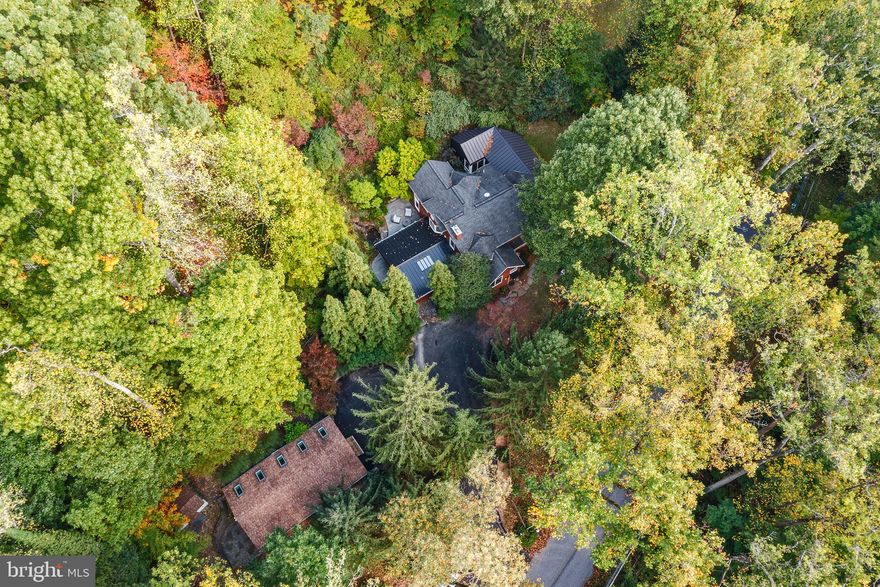 This remarkable 2.66-acre hideaway offers complete privacy while being just minutes from the heart of Wayne, King of Prussia Mall, and major highways like 202, 476, and 76. The open floor plan is designed to impress with soaring ceilings, walls of windows, and breathtaking expansive views.
As you enter, the 2-story foyer welcomes you into a grand living space that includes a spacious family room with a vaulted ceiling and abundant natural light, a formal dining room with a fireplace, and a newly remodeled kitchen featuring custom cabinetry and professional-grade built-in appliances. Adjacent to the kitchen is a bright breakfast room with sliding glass doors leading to a magnificent patio, lush landscaping, and a tranquil pond with a waterfall.
The main level also features a full bathroom, a half bath, and three bedrooms, one of which is oversized and boasts custom-built cabinetry, making it ideal for use as a family room, media room, library, or bonus space.
On the upper level, you'll discover a romantic loft with a 3-sided gas fireplace that overlooks the living areas below and offers stunning treetop views. This level also includes a luxurious master suite with a walk-in closet, private balcony, and an en suite bathroom featuring a soaking tub and separate shower.
The lower level exudes warmth with its exposed stone wall and cozy powder room.  It’s a great place to hang out.
Additionally, the property features a separate, versatile building—perfect for an office, studio, or gym. With high ceilings, wood floors, skylights, sliding glass doors, and independent electric service, this space offers endless possibilities.