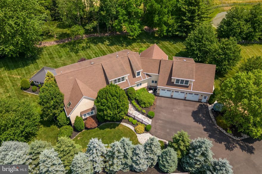 Nestled within the picturesque landscape of Bucks County lies a hidden gem—a luxury property that embodies elegance and sophistication. Situated on just over 3 acres, this remarkable home offers a tranquil haven for those seeking privacy and upscale living. With its impeccable design, top-of-the-line finishes, and prime location, it caters to the most discerning buyers, promising a lifestyle of opulence and comfort.
As you enter through the impressive 8-foot front double lead-glass doors, the grand foyer welcomes you with its ceramic in-lay floors, 10-foot high ceilings, and intricate woodwork. The foyer seamlessly transitions to the formal living room, adorned with Peruvian tigerwood flooring—a testament to the meticulous attention to detail that pervades every corner of this luxurious residence.
The open concept living area exudes an inviting ambiance, bathed in natural light that pours through the expansive windows. A stunning four-sided gas fireplace serves as the centerpiece, elegantly separating the living room from the dining area, creating a seamless flow for entertaining guests and hosting social gatherings.
At the heart of this extraordinary home lies the gourmet kitchen, a culinary enthusiast's dream come true. Equipped with high-end stainless steel Viking appliances, including a range with griddle and double ovens, the kitchen exudes both style and functionality. Granite countertops, a center island with a breakfast bar, beaded inset cabinetry, a trash compactor, and a stylish backsplash all contribute to the luxurious atmosphere. For added convenience, a central vacuum system with a toe kick crumbier ensures effortless maintenance.
The property offers several options to create a private study. One such space is the newly added flex room on the main floor, boasting a high coffered ceiling, transom windows, and French door access to the deck. This versatile room can be transformed into a luxurious home office, a cozy family room, or a hobby space.
The first-floor owner's suite epitomizes tranquility and elegance, featuring a spacious bedroom with scenic views. The primary bathroom is a sanctuary  complete with skylights, vaulted ceilings, a fully accessible walk-in shower, heated tile flooring, and a private commode. A large double walk-in closet, fully organized, offers ample storage space for your wardrobe.
In addition to the luxurious living spaces, a 2017  3-story addition brought even more enhancements to the property. Two massive 1st-floor walk-in pantries were included—one for all your Costco sized storage needs, and another with a full-size additional freezer and refrigerator. The thoughtful design and accessibility of the home, including 36-inch doors, ensure comfort & convenience for all. 
Venturing to the second floor, you can ascend either by stairs or by the Elevator, which takes you to a wide hallway adorned with Brazilian teak hardwood floors. Here, you will find another primary bedroom and three additional bedrooms along with three full bathrooms. A bonus room offering its own back staircase and private entrance near the garage, which can serve as an additional family room, a workout area, or an au-pair/in-law suite. The lower level of the property offers even more opportunities for entertainment and relaxation. Complete with a bedroom, a full bathroom, and ample living space, it boasts a full oak bar, multiple TVs, and a full workout room. 
Additional features include an alarm system with cellular backup, 2 water heaters, a backup generator, and music system that extends through the main floor, basement, and gazebo, barn and shed.
Outside, a captivating oasis awaits you. The Trex deck leads to a flagstone patio and a newly built 3-season gazebo. In 2021, the owners further enhanced the property by adding a new 6-7 car detached, heated, and finished garage with a lift and split systems with electric backup for heat . This addition caters to car enthusiasts, hobbyists or a home business.