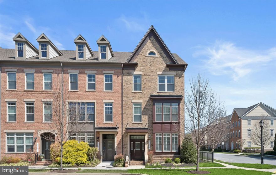 Nestled in the highly sought-after Maple Lawn community, this stunning end-of-row townhome built by Williamsburg Homes offers refined luxury, elegant design, and exceptional craftsmanship throughout.  Rich wood flooring and a neutral color palette define the main level, where the living and dining rooms are beautifully connected by a see-through gas fireplace. The gourmet kitchen is a true centerpiece, showcasing an oversized granite island breakfast bar with double sink, dark wood cabinetry, and stainless steel appliances, all flowing seamlessly into the adjacent family room with a second gas fireplace and access to the patio. A charming breakfast nook features rustic hanging barn doors that open to a functional mudroom.  All four bedrooms boast walk-in closets and private en suite full bathrooms, providing comfort and privacy for every occupant. The spacious primary suite offers a luxurious bath complete with a soaking tub and an oversized shower with built-in seating, and dual vanity. A second bedroom suite is also located on this level. The top floor features a large loft with a built-in workstation and two additional bedroom suites, ideal for guests, work, or relaxation.  Outdoor living is equally impressive with a private patio highlighted by a wall-mounted fireplace. A detached two-car garage and low-maintenance lot add everyday convenience.  Residents enjoy access to vibrant community amenities, including an outdoor pool, tennis courts, scenic walking paths, beautifully maintained common areas, and a welcoming dog park. Ideally situated just moments from everything Maple Lawn has to offer, this home provides convenient access to an array of shopping, dining, and everyday conveniences in one of the area’s most desirable neighborhoods.