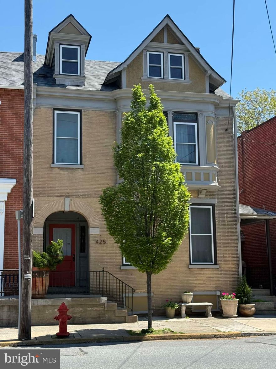 425 N Queen Street, Lancaster, PA

At last, the Lancaster City property you have been waiting for — a rare marriage of ornate historic architecture, fine craftsmanship, flexible living, and investment potential in one of Lancaster’s most dynamic mixed-use corridors.

Set along North Queen Street, this striking semi-detached residence immediately captures attention with its distinctive façade, brick archway, turret-style architectural detail, Tudor-inspired gable accents, and sandstone brick elements. Recently repainted and thoughtfully enhanced, the exterior blends historic presence with artistic charm. A truly unforgettable feature is the enchanting alley wall and gate — crafted with wood clapboard siding, cedar shake shingles, an ornate wooden door, and a whimsical hanging sculpture that evokes the feeling of stepping into a secret garden.

Inside, the home offers approximately 4052 square feet of above-grade living space, with additional lower-level and third-floor areas that expand the possibilities even further. A total of 5 bedrooms, 3 full bathrooms, 2 half bathrooms, a basement, finished third-floor space, patios, porch areas, a gazebo, pocket doors, crown molding, wood wainscoting, custom hardware, custom interior trim, decorative fireplaces, and 2-zone HVAC. 

Extensive renovations completed between 2020 and 2025 brought modern comfort and confidence to the home while preserving its architectural soul. Improvements include a remodeled kitchen, four new bathrooms, updated electrical, plumbing, heating, central air, an on-demand tankless water heater, approximately 80% replacement windows, and general renovations throughout. The kitchen is beautifully finished with fine custom cabinetry, beautiful upgraded countertops, and a layout that supports both everyday living and entertaining. The primary bath ensuite is especially impressive, featuring marble and tile finishes, a soaking tub, and a walk-in shower that creates a refined retreat within the home.

The floor plan is exceptionally versatile. The first floor includes an office suite adjoining a sitting room, with its own exterior entrance — an ideal setup for a professional home occupation such as a CPA, attorney, consultant, or private studio. For buyers seeking a live-work property, this layout offers both presence and practicality.

The second floor adds another layer of flexibility, with a separate exterior stairwell and independent ingress/egress leading to a portion of the home that could function as a one- or two-bedroom apartment with its own kitchen. Whether used for extended family, guest quarters, rental income, or future conversion, the layout creates options that are rarely found in a Lancaster City residence of this character.

The third floor offers additional bonus space, bedroom potential, loft use, studio space, or future renovation opportunity. The lower level provides approximately 1,400+ square feet of basement area, adding storage, utility, and expansion flexibility.

Outdoors, the property continues to impress with hardscaping, herringbone-patterned patio areas, select stonework, a gazebo, covered porch spaces, and garden-style features that feel private, curated, and unexpected for the city setting. The property also adjoins a parking lot and currently leases one parking space.

Zoned MU Mixed Use, the property may offer additional potential for multi-unit conversion, professional use, or short-term rental use, subject to buyer due diligence and municipal approvals. Based on the current layout, the home may have the potential to be subdivided into multiple units, with a possible three- to four-unit configuration depending on zoning, code, permitting, and design feasibility. Short-term rental p