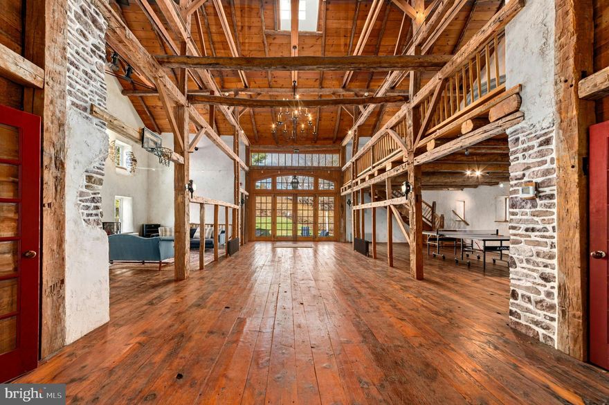 A magical living experience in the Bucks County countryside, this 1790s stone farmhouse on 13.6 acres offers vintage architectural elements updated with the modern amenities one would expect for luxe country living. Thoughtful additions and renovations over the years have created an elegant and well-designed country estate without compare. 
      The original farmhouse boasts antique accoutrements and architectural details such as exposed stone walls, 5 fireplaces, random width chestnut floors, beamed ceilings, period moldings and hardware, and deep windows with antique glass. Large covered porches in front and back feature herringbone brick, setting the stage for a home that seamlessly blends 19th-century soul with modern amenities. This stunningly restored and updated home  is a masterclass in combining historic charm with sophisticated living.  A recent addition includes a sunny, oversized kitchen with vaulted ceiling, clever built-in storage, and a breakfast nook that looks out over the idyllic countryside. A den, living room and guest suite with bath complete the first floor. Upstairs, the primary suite includes a newly refurbished bath and stylish dressing room/walk-in closet with built-in storage, and access to the balcony for enjoying a morning coffee or evening cocktail accompanied by long-distance views. Completing the upper floors are three additional bedrooms and a hall bath.
     The swimming pool, dramatically positioned amidst long-distance vistas, offers a pool house with bar and sound system. Herringbone brick decking around the pool is set off by split rail fencing and manicured box hedges, creating a sophisticated space for parties, guests, or quiet evenings with family. Near the main house is a circa 1790 stone summer kitchen with 2 pizza ovens and Argentinian wood grill. A detached garage provides covered parking, while a sunny and spacious 2nd floor serves as artist’s loft or private office space, complete with wood stove and half bath.
     Multipurpose buildings are perfectly positioned amidst the rolling acreage, overlooking vistas of manicured horse pastures. The stone bank barn, breathtakingly restored, provides an amazing vaulted space for entertaining in large numbers, as well as a media loft, studio space, and caterer’s kitchen. Adjoining this multipurpose space are guest quarters with a kitchenette, two full baths, and a private balcony. 
     Equestrian facilities include a well appointed 5-stall stable and heated tack room with built-in storage. An outdoor arena and 2 fenced pastures blend seamlessly into the thoughtfully landscaped acreage, accented with herb, vegetable, and rose gardens. 
     A rare mix of secluded tranquility and easy access to nearby towns, Windhorse Farm is just 90 minutes to Manhattan and under an hour to Philadelphia.