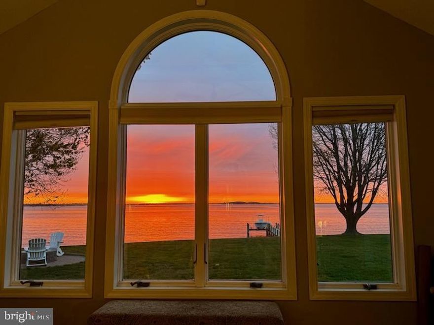 Welcome to waterfront living at its finest in the highly sought-after Southwind community on Kent Island, where this stunning home offers one of the most breathtaking views of Crab Alley Bay. Perfectly positioned with an east-facing orientation, you'll enjoy spectacular sunrises that paint the sky and reflect off the water each morning.  This beautifully designed 4-bedroom, 2.5-bath residence blends comfort and elegance with panoramic bayfront vistas from nearly every room, including the living room, dining room, sun-drenched sunroom, and family room with a warm and inviting stone fireplace. The main level features three well-appointed bedrooms and 1.5 bathrooms, while the upper level is home to a serene, newly carpeted bayfront primary suite complete with an ensuite bathroom, walk-in closet, and a versatile loft space ideal for a home office or reading nook.  The kitchen is as functional as it is stylish, boasting granite countertops and a suite of new and newer stainless-steel appliances. Additional recent upgrades include a new washer and dryer, newer windows (majority) and marine grade sliding glass doors (2024), a 2024 gas furnace, and an on-demand gas water heater—ensuring year-round efficiency and comfort.  Step outside to your private waterfront paradise, where a spacious deck invites family gatherings and summer barbecues, and a cozy hardscape feature with a space for your crab feast table and a custom firepit sets the scene for relaxing evenings under the stars. The pier has been thoughtfully updated with new decking and a brand-new boat lift, ready to launch your next adventure on the bay. An oversized two-car garage provides ample space for vehicles and storage.  Whether you're entertaining outdoors, soaking in the views from the sunroom, or heading out for a day on the water, this home captures the very best of Chesapeake Bay living.