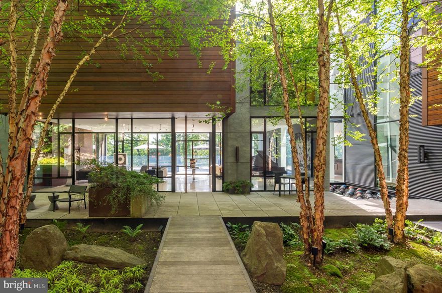 Overlooking the Potomac River in scenic Glen Echo, Wissioming Road is a modernist masterpiece designed by the critically acclaimed Robert M. Gurney, FAIA. In the architect’s signature style, interconnected structures harmonize with the site’s natural topography to create a striking visual cohesion and uninterrupted views of the roaring river beyond. A spectacular addition by Christopher Tucker, constructed by Steve Howard of Square One Development, enhances Gurney’s original vision of Corten steel, rich wood, and expansive glass. The approach is both bold and intentional—anchored by a generous covered carport and an attached, heated four-car garage, offering exceptional space for the automobile enthusiast. A bridge crosses whimsical, High Line–inspired landscaping in the central courtyard, leading to the home’s dramatic main entrance. Inside, the main living area is a masterclass in luxurious minimalism. Slender steel window frames—laid out in a Mondrian-inspired pattern—frame sweeping views of the Potomac, while large, unbroken slabs of white terrazzo flooring reflect natural light to heighten the sense of space. Rich mahogany paneling conceals the television, and a floating bamboo vanity distinguishes the formal powder room. An adjacent screened-in porch with its own fireplace and television allows for four-season enjoyment. The chef’s kitchen is nestled beneath an upper-level mezzanine, illuminated by double-height, floor-to-ceiling windows with motorized shades. Sleek European Varenna by Poliform cabinetry conceals a suite of professional-grade Miele appliances, subtly accentuated by architectural Delta lighting. The space opens into a generous dining area, perfectly positioned to overlook the central courtyard and create a seamless indoor-outdoor experience. A full butler’s pantry with redundant appliances and access to the three-level elevator complete the main level. A floating steel staircase leads to the upper level, introduced by a frosted Shoji-paneled wall. Three secondary bedrooms—each with an ensuite bath and walk-in closet—are connected by a shared sitting room. The primary suite commands its own private wing, accessed via a floating glass bridge. Stained ebony floors and two private offices set the tone for the refined sanctuary that follows. Sweeping river views pour into the main sleeping area through floor-to-ceiling windows and continue onto the full-length private balcony, while custom blackout curtains allow for serene retreat. The limestone-clad bath is a study in indulgence, featuring a freestanding tub set against glass, a walk-in shower, sauna, and a separate dressing room. On the lower level, the main recreation area spans more than 52 feet. Polished concrete floors, a wet bar, and a temperature-controlled, illuminated 1,000-bottle wine cellar create an effortless environment for entertaining. In the opposite wing, a professional fitness center with padded flooring, its own HVAC system, and a Helo sauna connects to a fully self-sufficient guest suite complete with private bath, patio, and kitchenette. The lower level’s architectural pièce de résistance is a split-level library. A cozy upper-tier reading nook accesses a cantilevered glass bridge that overlooks the dramatic den below. An unbroken wall of built-ins spans both levels, anchored by a linear gas fireplace and double-height window wall with direct access to the lower patio. Out back, a magnificent 66-foot lap pool serves as the property’s showstopping centerpiece. A built-in grill and fireplace on the rear terrace facilitate al fresco entertaining, framed by dramatic views of the Potomac. An interconnected fortress of luxury, the residence features computer-controlled Lutron lighting, Sonos surround sound, Honeywell security, and video surveillance. Ten zones of HVAC, a whole-house Generac generator, and copper plumbing speak to the thoughtful engineering and enduring quality behind the home’s construction.