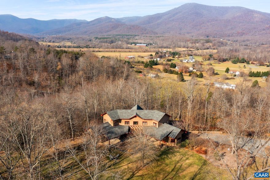 Located in the heart of Nelson County this spectacular 14 acre private estate, Graceland, overlooking Rockfish Valley and Blue Ridge Mountains is everything you are hoping to find. The elegant custom built home was carefully placed at the end of a gradual drive on top of a ridge in an open meadow allowing for ease in access with space to add gardens, orchards, vines, a pool or maybe a pickle ball court! From the moment you enter the magnificent light filled Great Room with soaring 25' ceiling, wall of glass to view, antique heart pine floors, post and beams with wrought iron and floor to ceiling stone fireplace, you will appreciate the fine quality, superb workmanship and exquisite taste that went into making this magnificent home. Entering the gourmet kitchen with stone fireplace, marble counters, custom cabinets and chef appliances you see yourself entertaining friends and family in your home here. Designed for one level living the office with Murphy bed, powder room, laundry and large primary suite flow together. Upstairs are 2 guests, den and bath. Downstairs a rec room, 2 BRs 2 baths and garage. Within minutes to Wintergreen, skiing, golfing, AT, wineries, breweries, and C'ville why wait? You deserve to be here now!,Glass Front Cabinets,Marble Counter,Painted Cabinets,Fireplace in Great Room,Fireplace in Kitchen