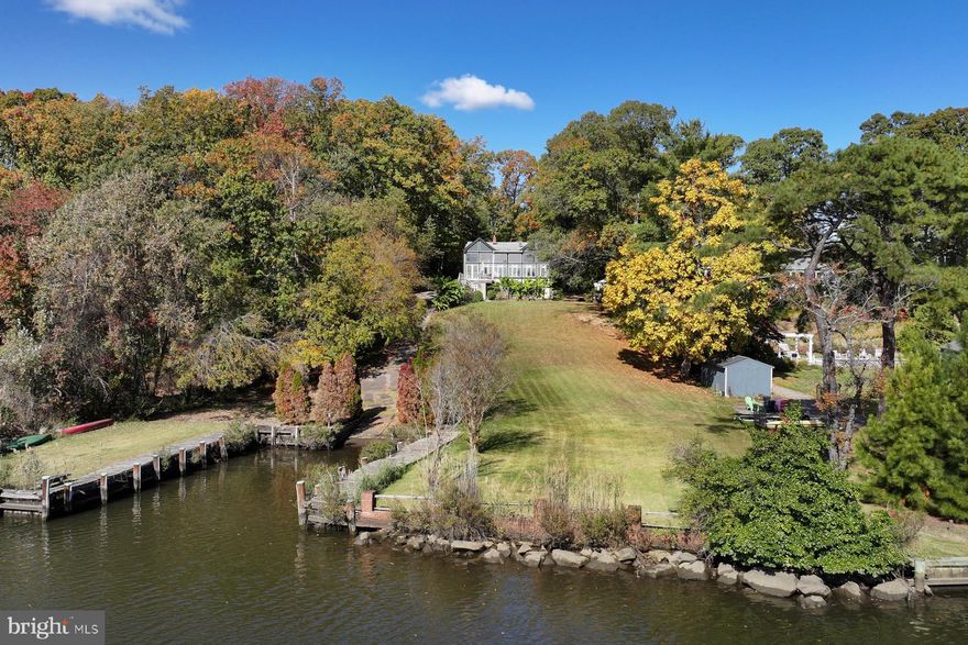 Discover one of Severna Park’s most private waterfront settings. Set on a .69 acre lot at the end of a quiet cul-de-sac in the Longmeadow community, this Tudor-style home offers exceptional indoor–outdoor living, peaceful water views, and privacy on Cypress Creek.
The Tudor home’s two-story foyer is distinctive, with beautiful wood detailing and terrazzo flooring. On the waterside beyond the entry, the spacious kitchen opens directly to the family room. The space is anchored by a two-story wall of windows overlooking the water, creating the central gathering space of the home. Step out onto a large deck from the family room for seamless indoor-outdoor entertaining and enjoy an easy stroll down to the water. A formal dining room with hardwood floors leads to the adjoining living room with a wood-burning fireplace. The rooms are graciously proportioned. A den at the front of the home provides a quiet workspace with peaceful views of the front yard.
The bedroom layout offers valuable versatility. The primary suite, with ensuite bathroom and balcony overlook, and two additional bedrooms are located together on the upper level above the foyer. An additional bedroom is accessed by its own staircase off the living room, making it ideal for guests, in-laws, or an au pair. The fully finished walkout lower level includes a full bathroom, large recreation room, and a potential additional bedroom. It extends the living space even further and connects directly to the waterside patio.
Mature trees, thoughtful landscaping, and Cypress Creek waterfrontage create a true waterfront retreat. The gentle slope to the water puts the home at an ideal elevation without making water accessibility a challenge. The private boat ramp is a unique feature and allows the owner to take advantage of launching a boat at their convenience. 
Even with its extraordinary privacy, the location remains exceptionally convenient. Severna Park schools, Kinder Farm Park, the B&A Trail, and shops and dining are minutes away. Commuters benefit from easy access to Annapolis, Baltimore, and Fort Meade, while boaters will enjoy the quick, scenic run from Cypress Creek to the Magothy River and out to the Chesapeake Bay. This is a rare opportunity to own a classic home in a private setting, with peaceful water views and deep-water access in the heart of Severna Park.