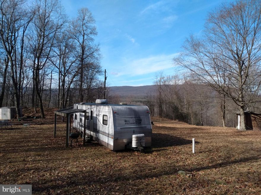 WV Paradise! 10.34 Acres of Private Mountain Land with Views, level build area and unique features. 2004, 30 ft camping trailer, bump out design and looks to be in great shape! Electric, and septic system in place, this land ready to use now. Not far from Cacapon / Potomac River state access points.  Perfectly level area for camping or building your cabin, with mountain laurel that will be flowering this spring.  The ridge has been used as a quarry 100 years ago and offers many interesting features today, a great place to search for fossils. Good hunting and shooting within the property and public hunting land is not far away. There are two lots here making this an excellent investment. Call Today!
