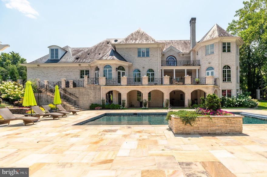 Located in the heart of Potomac Village, just two blocks from shops and restaurants, this exceptional residence epitomizes a flawless blend of architectural brilliance, high-end finishes, and modern amenities. Designed by an award-winning architect and completed in 2011, this luxurious home masterfully integrates timeless elegance with contemporary comforts. Spanning over 11,000 square feet across three meticulously finished levels, it offers grand scale living and entertaining, while also providing a warm, inviting interior thoughtfully designed for the comfort and enjoyment of family and friends.  The MAIN LEVEL is anchored by a stunning  front-to-back foyer, where a magnificent staircase with handcrafted wrought iron balustrades sets a welcoming ambiance for the owners and visitors.  The formal living and dining rooms exude sophistication, while the chef’s kitchen, with its high-end custom cabinetry and top-of-the-line professional style appliances, stands as the heart of the home. A spacious walk-in pantry and a convenient butler’s pantry enhance the functionality of this culinary haven. Adjacent to the kitchen, a spacious family room with walls of windows and a gas fireplace provides a perfect space for everyday activities. The stunning mahogany-paneled library features built-in bookshelves, a coffered and hand-painted ceiling, a gas fireplace and offers a serene retreat for work, reading, or quiet reflection. Tucked at the end of the hallway, the main level guest bedroom with an en-suite bath ensures that visitors enjoy both comfort and privacy.  Many of the main level rooms beautifully flow outside onto the expansive terrace through an array of oversized French doors creating an ideal setting for outdoor dining and entertaining. The UPPER LEVEL features four generously sized en-suite bedrooms, including the luxurious owner’s suite. This retreat boasts a spa-like bathroom, two walk-in closets, and access to a private balcony overlooking lush gardens. An additional bonus room/bedroom on this level offers flexible use, whether as a studio, office, or a bedroom. The WALK-OUT LOWER LEVEL is tailored for both entertainment and relaxation, featuring a state-of-the-art home theater, various gathering spaces, and a custom-designed bar that creates a vibrant, club-like atmosphere. It also includes two en-suite bedrooms, perfect for accommodating guests or serving as a versatile space for an in-home gym.  OUTSIDE, the property continues to impress with two large loggias featuring wood-burning fireplaces, a sleek black-bottom swimming pool, and amazing waterfalls. The garden is truly exceptional and arguably one of the most stunning in Potomac.  Its charm and allure are truly beyond words—be sure to check out the photos to fully appreciate its breathtaking beauty!