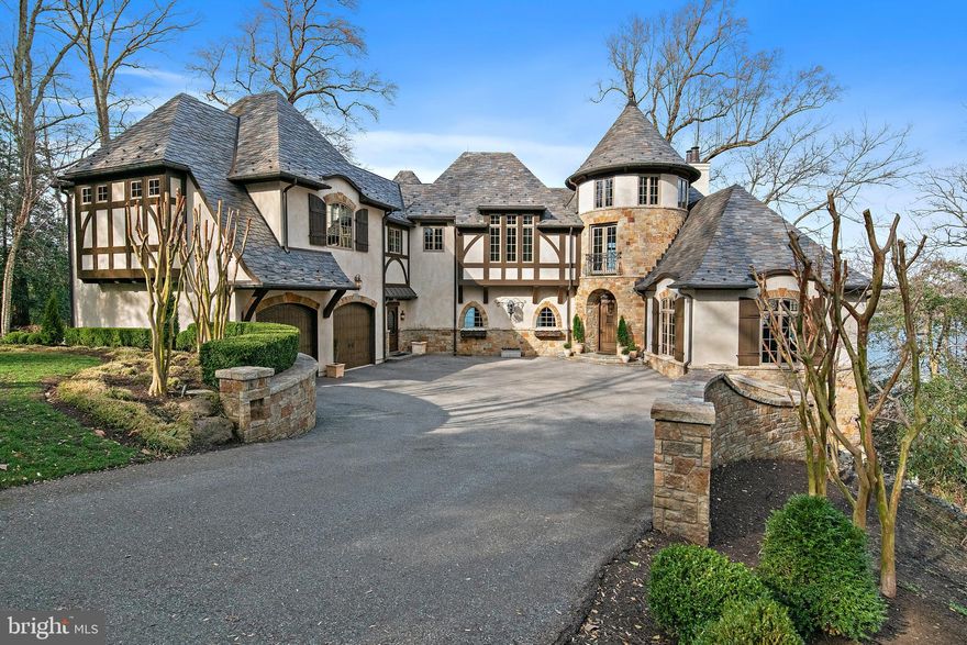 Set on 4.5 scenic acres along the Severn River, this exceptional Tudor/French Country estate blends timeless architecture with high-end craftsmanship just 10 minutes from downtown Annapolis.

Light-filled interiors showcase sweeping water views and a seamless floor plan designed for both everyday living and entertaining. A dramatic curved staircase anchors the foyer, while the main level offers a gourmet kitchen, living room with stone fireplace, bar, office, mudroom, two powder rooms, and dining room.

The chef’s kitchen features a 6+ burner Wolf range, hammered copper sinks, dual dishwashers, ample prep space, and a large pantry. The living area opens to a spacious deck, perfect for waterfront entertaining.

Upstairs, the primary suite includes a wet bar,  private balcony, two walk-in closets, dual vanities, and a walk-in shower. This level also offers flexible bonus space, two additional bedrooms, laundry, and a full bath.

The lower level adds two more bedrooms, two full baths, a family room with fireplace and bar, and a game room—all with easy outdoor access and river views.

A rare opportunity to own a meticulously crafted waterfront retreat combining old-world charm with modern luxury.
