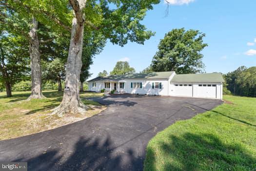 TAKE ME HOME COUNTRY ROADS....Escape the hustle and bustle and embrace the peace and tranquility of country living with this beautiful ranch style home nestled on just under 10, mostly cleared, usable acres . Whether you're dreaming of a hobby farm, building your equestrian paradise, or just enjoying wide open space, this property is your perfect match. About 8.5 acres is ready and waiting for livestock, gardening or recreation (about one half acre is already fenced with 4 board and welded wire fencing for dogs). (There's a smaller fenced area within a larger fenced area). Located on a dead end, quiet, rural road, you will still be within easy reach of town conveniences, schools, and major highways. Experience the best of both worlds- peaceful seclusion plus everyday accessibility. This spacious Ranch Home boasts 3 very large Bedrooms and 2 huge Full Baths. Gleaming Hard Wood floors are showcased throughout most of the house as well as including a palatial Laundry Room with a Plexidor doggie door leading out to a small porch and fenced yard. This country paradise produces well water that has never tasted so good, originating from a deep natural spring - it runs all year and never goes dry (the capped spring head is located on this property). Amazingly, there's also great potential for a beautiful spring fed pond at the rear of the property, PLUS, as if not enough, this parcel can also be divided should you ever wish to add another residence....think mother-in-law, tiny house or whatever! At the rear, there is also a 24x30 sq ft Garage/Barn to store those tractors or park two more vehicles. Attached to the house is another two car, over sized Garage with extensive shelving and storage. As a much sought after one level home, you can enjoy family meals in the large eat in Kitchen (Refrigerator 2022, Dishwasher 2022, new granite counter tops and sink 2025) or the formal Dining Room. A spacious Living Room, Family/Recreation Room (new flooring and mini split 2025), and the Library (could be play area, den, office) completes the home's configuration. Other improvements include, but not limited to, running electric to the barn (2024), foundation reinforcement (2025), new Hot Water Heater plus brass fittings (2023), ADA compliant toilets (2022), freshly painted interior (most of house 2025), new Bathtub and Sink fixtures (2024), HVAC completely serviced in last 6 months) and the piece de resistance is the Hardwired Fiber Optic Internet (FiberLync) for those who may work from home!! Majestic century old oak trees grace the front of the home, their sprawling canopies offering shade, character, and a timeless sense of grandeur as you listen to the sounds of birdsong, breathe in the fresh air, and soak in the stillness from the covered front porch, embracing nature at its finest. (new posts and roof 2025). Whether you're dreaming of a weekend retreat, homesteading or simply a place to enjoy life's quiet moments, this property delivers: Peace, Serenity and Tranquility! Don't just read about this exceptional property, come to see it in person....Run, don't Walk...this will go fast!!