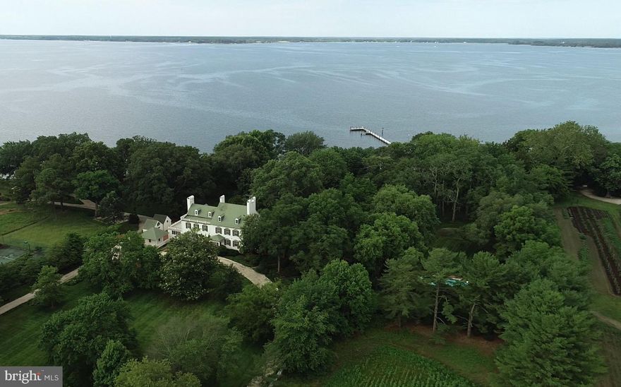 Wilderness Estate- REVISED OFFERING INCLUDES 5 PARCELS 6.27.25- This quintessential Eastern Shore farm is located along the Choptank River in Trappe, Maryland. Comprised of 234 acres, with original structures that are impeccably well-kept and improved with modern amenities, The Wilderness provides a unique opportunity to enjoy the best of the Eastern Shore.  Surrounded by open space and preserved farmland with proximity to Oxford, Easton, Cambridge, and St. Michaels, The Wilderness is sure to please the discerning buyer.  
Sited among large waterfront estates, The Wilderness enjoys privacy and a commanding presence with old-growth trees, broad southerly views, and deep water.  The scope of improvements includes the primary residence, waterside guest cottage, beach house, pool, pier, tennis court, early 20th-century barn, and a host of accessory structures for life on the farm.  Visit the virtual tour for an inside look and appreciation for the scope of this offering.

The main house has great historical significance not only for the original owner’s grandson who lived there and served two terms as the Governor of Maryland but also for its place in the development of Maryland’s domestic architecture, as noted on two markers from the Maryland Bicentennial Commission and the Maryland Historical Society. 
The smaller and original of the two brick wings dates from the late 18th century and the larger wing from the early 19th century. The house’s architecture is unusual in that the 19th-century wings telescope up, instead of down, from the original wing. The white brick, black shutters, and historical olive green trim color are a serene palette against the house’s majestic specimen trees around the property, including a gigantic Sycamore that is the largest of its species in Maryland. 
The long white gravel drive under the sheltering canopy of mature trees passes by the barn and other outbuildings then curves around the front of the house. Brick steps lead up to the front porch of the early 19th century wing opening into a gracious foyer and stair hall with an elegant elliptical arch that rests on pilasters at the side walls to separate the public from private areas of the house. A French door at the rear of the foyer frames a vista of the lawn and Choptank River. To the side of the foyer are two identical parlors at the front and rear corners of the house. Both rooms have magnificent fireplace mantles and surround; one is a 1740 hand-carved mantel by noted English artisan woodcarver Grinnling Gibbons and the other is a 1780 mantel surrounded by the famous English architect and artisan, Robert Adam. 
The main floor of the 18th-century wing contains a spacious living room, dining room, original kitchen, and larger kitchen, pantry, two powder rooms, and a stunning sunroom connecting to a terrace along the rear of the house overlooking the Choptank River. Part of this wing was the final addition to the original home.
The second floor of the 19th-century wing contains two bedrooms over the two parlors below with fireplaces and walk-in closets and two baths. The 18th-century wing and later addition contain an artist’s studio with cabinetry and sink that has a myriad uses– TV room, arts and crafts room. The primary suite is located at the rear corner of this wing. It has a fireplace flanked by single windows and another window on the rear wall for panoramic views of the mature landscape and the Choptank River. Two baths complete the suite, with one bath off a hall for access from the art studio. 
Two stairs access the attic level; one in the 18th-century wing leads to two bedrooms and one bath. The main stair in the 19th-century wing leads to a large game room and another cozy bedroom ensuite.

The revised offering of The Wilderness, providing 234 acres comprised of 5 recorded parcels with over 3,000 feet of shoreline is a remarkable opportunity to witness life on the Shore.