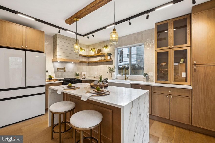 Welcome to this stunning brand new renovation 3-bedroom, 3-bathroom home in the center of Fishtown with 10 year tax abatement, offering a perfect blend of character, style, and modern upgrades. This home showcases engineered hardwood flooring throughout and thoughtful design touches at every turn. The spacious living room features reclaimed beam feature, a shiplap wall accent, milk glass accent lights, lit niches highlighting original brick details, and glass wall divider along staircase. The open-concept dining area flows seamlessly into the chef’s kitchen, complete with plentiful cabinetry including a full pantry, a quartz waterfall countertop, island with seating, upgraded matte white appliances including gas range with pot filler, custom vent hood, large farmhouse sink overlooking backyard, reclaimed wood open shelving, and abundant backsplash tile. Step outside to enjoy a  backyard with a wood fence and private access. On your way upstairs you will see upgraded stair lighting, hanging accent light, and wall mounted feature lights. The second floor offers a full hall bath with tiled tub surround with an accent niche with lighting. The rear bedroom is generously sized with a closet with built ins, while the front bedroom includes an original brick niche, nice sized closet , and bedside lighting..  The third floor features a dry bar with mini fridge. The show-stopping primary suite boasts a large lime-wash lit feature wall with built-in niches, bedside lighting, accent light, plentiful closets with built ins, barn door leading to a luxurious primary bathroom featuring a reclaimed wood double vanity, oversized custom shower with frameless glass doors and niche lighting, and a freestanding soaking tub. The massive roof deck features built in speakers, plenty of lighting, and generous city and bridge views. The finished basement expands the living space, perfect for a second living area, home office, or gym and includes full bathroom with tiled shower.  Located in the most residentially dense section of Fishtown and a short walk to all sought after amenities . Schedule your showing today!