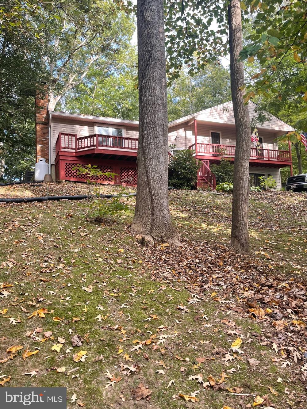 Price Improvement!!! Enjoy your own private gem located up a secluded asphalt lane, featuring a 3-car detached garage and a stunning 4-level split home. The large living room boasts hardwood flooring, recessed lighting, and a cozy brick wall with a gas fireplace. The space seamlessly flows into the new kitchen and open dining room, complete with quartz countertops, gray cabinets, stainless steel appliances, and a spacious pantry. The primary bedroom offers a new luxury bath, while two additional bedrooms feature balconies and share a new hall bathroom. The ground level walkout family room includes ample closet space and a versatile den that can serve as a 4th bedroom or in-law suite, with an adjoining new full bath and laundry room. The fourth level offers a partially finished recreation/playroom and a large storage/workshop space. Outdoor living is a delight with a 52x14 paver patio, complete with a hot tub, a wooded pergola, and a firepit to enjoy the tranquil surroundings. The property backs to a private nature area with a stream below. This home provides easy access to a community beach just blocks away, featuring a pier, boat ramp, and picnic pavilion on the Patuxent River. Walk or ride your golf cart to this serene retreat and enjoy all the amenities it has to offer.