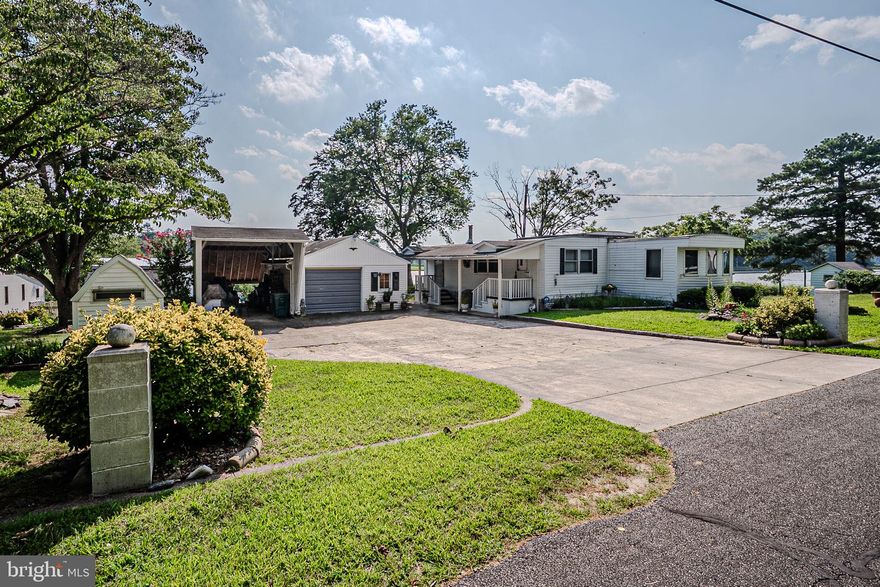 Welcome to Water Views & Gorgeous Sunsets in the Fan Favorite Community of Possum Point. No lot rent here! Homes in this community are on OWNED LAND. This great 3 Bedroom manufactured home with two factory additions welcomes you with white piers that mark the property boundaries, a covered porch, private driveway, and several outbuildings. Enjoy the warmth of the pellet stove during chilly Fall & Winter nights in the welcoming Family Room, or entertain your guests in the comfort of the Living Room. This home has plenty of living space!  The Kitchen is equipped with gas stove, double sink, dishwasher, microwave and refrigerator.  Off the kitchen you'll find the Formal Dining area with built in cabinetry and laminate floor. Down the hall are two small guestrooms, just large enough for a standard twin bed with built in dressers and closets or use as an office, study or other flex space. The Hall Bath has a double sink vanity and bathtub and the PrimaryBedroom is lined with windows so you can appreciate the gorgeous views of the water and evening sunsets.  Water views can be seen from multiple locations within this great home. There is also a spacious laundry room that has plenty of cabinetry, shelving and a utility sink for all your cleaning and storage needs.  Outside is a large  Boat/Carport, 1 Car Detached Garage, Shed, and Large 23x24 Pole Building. All of this and only a short five minute drive to all the conveniences of Downtown Millsboro. Use as a Primary Residence Year Round, or as a Summer Retreat Home until you're ready to build your Dream Home on this great lot. This completely livable home is being sold As-Is, Where-Is, without Seller certified septic due to unknown age of system and no available information on file with DNREC. Existing system is currently functioning. Property previously tenant occupied and vacated in May 2025.