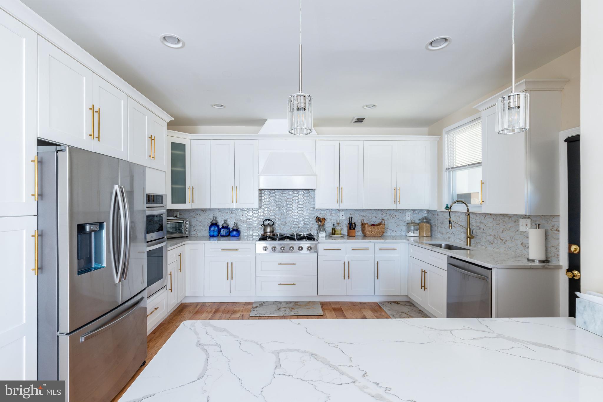 Historic Elegance Meets Modern Luxury in the Heart of Lansdowne. Welcome to your dream home in the beloved Henry Albertson Historic District—a masterful blend of timeless charm and contemporary design. This expansive 3-story residence offers 5 bedrooms, 4.5 baths, and a beautifully reimagined layout designed for modern living. Step onto the wide, covered front porch—perfect for relaxing evenings or morning coffee—and enter a fully renovated interior where every detail has been thoughtfully updated. Gleaming hardwood floors flow throughout, complemented by brand-new electric, plumbing, HVAC, and a showstopping chef’s kitchen that anchors the open-concept main level. The first floor invites effortless entertaining with spacious living and dining areas leading to a gourmet kitchen featuring white shaker cabinetry, a premium 6-burner THOR gas range, stainless steel appliances, and even a built-in beverage fridge. A stylish half bath completes this floor. Upstairs, the second level boasts a luxurious primary suite with a spa-inspired en suite bath, plus a generously sized second bedroom and full guest bath. The third floor offers two more bedrooms—one with its own en suite—and a hallway bath, ideal for family or guests. Need even more space? The fully finished basement doubles as a second living suite, complete with a sleek modern kitchen, bedroom, and full bath—perfect for in-laws and guests. Outside, enjoy a private, fenced backyard designed for year-round entertaining. Live just steps from the best of Lansdowne: stroll to the vibrant Farmers Market, catch live music or an art show, and explore local gems like the Symphony Orchestra and Folk Club. You're also just minutes from University City, I-95, and the Philadelphia Airport—close to everything, yet peacefully tucked away.