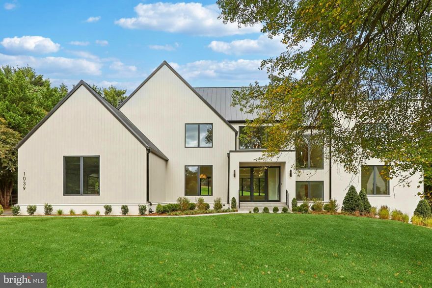 Nestled in the heart of Great Falls, this modern transitional masterpiece, designed by Harrison Design and constructed by Palladio & Co., offers an unparalleled living experience. With a dynamic, open floor plan bathed in natural light, it effortlessly 
blends traditional elegance with contemporary convenience.  Spanning approximately 9,545 square feet across three meticulously finished levels, this architectural gem is a designer’s dream, featuring state-of-the-art finishes and thoughtfully curated details throughout.
As you step inside, your eyes are naturally drawn through the space, guiding you toward the level manicured green lawn at the back. The grand two-story vaulted foyer is highlighted by a sculptural curved-rail staircase and elegant designer lighting, 
setting the tone for the entire home.  The kitchen is a chef’s delight, featuring a statement 48” AGA range, paneled 
appliances, and a striking stone island, with a spacious scullery kitchen designed for prep work. The great room, centered around a linear gas fireplace with a floating hearth, creates a cozy and inviting atmosphere. The sun-soaked casual TV/morning room features floor-to-ceiling retractable glass sliders, seamlessly blending the interior with the outdoor living space and framing views of trees and nature. The expansive covered outdoor areas and patio are perfect for both intimate evenings and seasonal gatherings, with the potential to add a pool, spa, grill station, outdoor fireplace, or fire pit. The main level also features a formal dining room, a luxurious owner’s suite with a spa-inspired bath complete with a dual sink vanity and Graff fixtures, a home office, and a convenient mudroom leading to the oversized attached three-car garage with 
two EV chargers, adding both function and elegance to the space.
On the upper level, the exceptional primary suite offers a serene sanctuary with a freestanding soaking tub, a curbless glass-enclosed shower with fluted tile, and heated radiant floors. Multiple walk-in closets and a dedicated makeup center 
complete this retreat. This floor also includes three additional ensuite bedrooms, each with custom tile baths, a laundry room and abundant storage for linens.
The lower level is designed for relaxation and entertainment, featuring an open recreation room with ample natural light and easy access to the yard. The full wet bar, complete with a tall wine cooler and refrigerator, sets the stage for hosting, while the separate gym/exercise room provides an ideal space for fitness. The home theater or optional golf simulator room is pre-wired and ready for enjoyment and a private ensuite craft room (or 6th bedroom) adds the finishing touch to this floor. An optional elevator can also be added for convenience.  Every detail has been thoughtfully crafted, with custom design elements throughout.  This exceptional home offers the perfect balance of serene living in Great Falls with easy access to fine dining, shopping, and more.  Prospective buyers are encouraged to reach out to Listing Team to inquire for further information about the distinctive features and key specifications of this remarkable property and schedule a tour.  Make sure to refer to the Documents section for th eBrochure and Floor Plans.