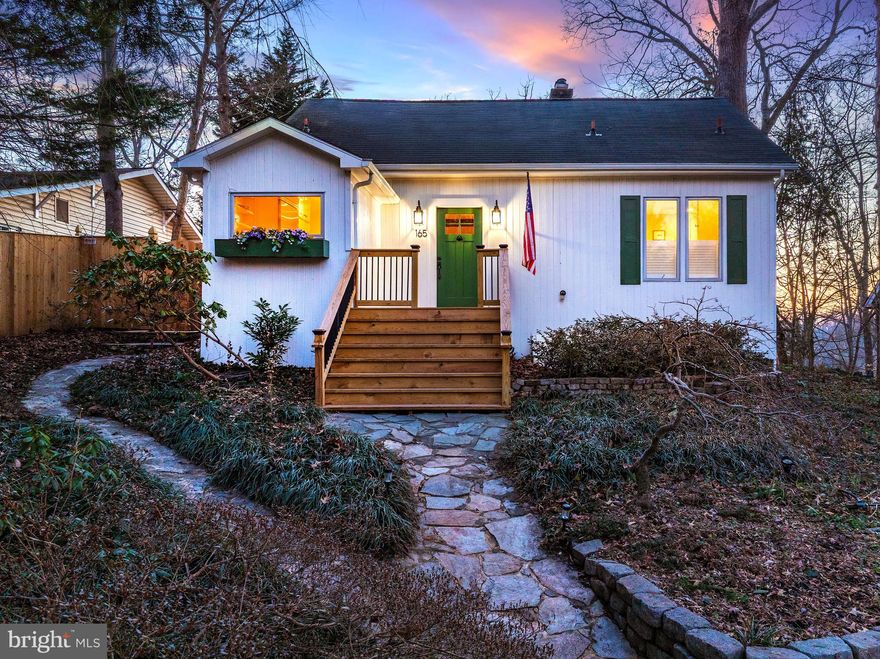 Welcome to 165 Severn Way — a charming, fully reimagined 1935 Chesapeake cottage ideally located just a short walk to the community beach in the coveted Lower Pines of Pines on the Severn. Perched among the trees and filled with natural light, this charming home blends timeless coastal heritage with modern luxury, offering the perfect balance of character, comfort, and convenience.
Originally a 1930s bungalow, the home was completely transformed in 2021 into an open, airy, and thoughtfully designed living space. The renovation included a new layout, updated kitchen and baths, a finished lower level, and extensive exterior improvements. Inside, you’ll find beamed ceilings, reclaimed pine floors throughout all living spaces and bedrooms, custom reclaimed wood doors and millwork, quartz countertops, marble tile, frameless glass shower doors, custom cabinetry and vanities, and abundant recessed lighting that makes every room glow.
Designed for comfort and flexibility, the home features two full primary suites—ideal for empty nesters, couples, young families, or hosting guests with privacy. The chef’s kitchen anchors the bright living spaces, preserving the warmth and charm of the original cottage while elevating it with refined finishes and a sophisticated Chesapeake aesthetic.
The finished lower level adds approximately 500 square feet of versatile living space, perfect for a gym, media lounge, playroom, or additional guest area.
Outdoors, the property is equally impressive. Recent improvements include updated siding and trim, new gutters, soffit and fascia, a new front deck, expanded driveway with pebbled parking area, new fencing, and extensive tree work. Tiered landscaping surrounds a two-level stone patio with an exterior TV and water views—an exceptional setting for entertaining, grilling, morning coffee, or sunset cocktails overlooking Chase Creek and the Severn River.
Nestled into the cliffs of the Severn, Pines on the Severn is a classic, eclectic community originally designed for summertime living for those in DC and Baltimore. It’s an active community with long-standing traditions and this home is nestled between its best features: a short walk to the playground, tennis and pickleball courts, but an even shorter walk to the sandy beach and marina. Pool memberships are also available a short golf cart ride away. 
This is a rare opportunity to own a beautifully restored historic bungalow in one of Arnold’s most desirable, walkable waterfront neighborhoods—where charm, craftsmanship, and lifestyle come together seamlessly.