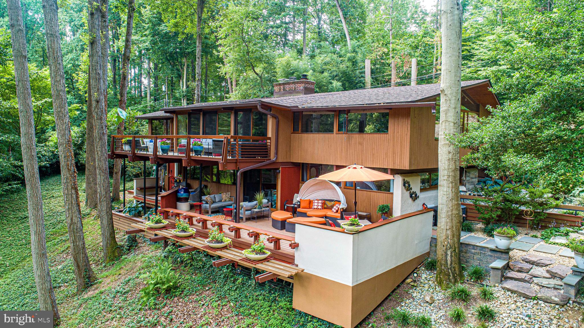 Welcome to this exquisite 1971 Acorn Deck House. This mid-century modern-inspired Deck House
sits on a private one-acre wooded lot backing to parkland above the Loch Raven Reservoir. The post-
and-beam home has been a complete top to bottom custom renovation by its Architect owner, who
has meticulously restored and maintained the home and is now proud to present it to the market.
Deck House as a company was founded in 1959 by William Berkes and Robert Brownell. Both
worked as young architects focused on building prefab Tech-built houses; this was the beginning of
the Mid-Century modern movement. Modern technology combined with the organic principals to live
in harmony with nature as envisioned by Frank LLoyd Wright gave birth to the Deckhouse.
The company, still in existence in Acton Massachusetts as Acorn Deck House, describes the design
this way: “Deck House offers an efficient post and beam building system with exposed structure,
making a powerful statement of beauty, strength and function. Floor to ceiling glass frames connect
with the natural environment to create a feeling of living in the outdoors. Interior spaces flow freely,
accented by a rich combination of natural woods. Deck House is a quiet statement about one’s own
self-confidence – a home of relaxed elegance in perfect harmony with the natural world, inside and
out.”
With 3300 square feet of living space spread across two levels of architectural excellence, offering
three bedrooms and two fully renovated bathrooms, this property offers the perfect combination of
style, space, and comfort. As you step inside, you'll be impressed by the incredible build quality and
attention to detail that's evident throughout the home. The exposed beams, cedar roof deck, and solid
mahogany doors and windows are a hallmark feature of the Acorn Deck House; together they add to
the sense of grandeur and sophistication. The large windows invite natural light to flood the space,
creating a bright and airy ambiance. The design emphasizes the connection to nature; every wall has
expansive open glass walls that overlook into the forest of tall red oak, white oak, hickory, and tulip
poplar trees. The change of seasons become the walls –natures art that make this home truly
integrated inside and out.
The tastefully decorated interior boasts clean lines and a minimalist aesthetic that perfectly
complements the mid-century modern architecture. The open-plan living areas are perfect for
entertaining guests or spending time with your family, while two cozy fireplaces creates a warm and
inviting atmosphere on chilly evenings. The updated kitchen features stainless steel appliances,
granite countertops, an entertaining island, and ample storage space, making meal preparation a
breeze. There is also a side coffee and cocktail prep area with eat-in breakfast table; this leads you to
your outdoor dining room right off of the kitchen, with easy access to your outdoor grill. This is an
entertainment gem.
The bedrooms offer plenty of privacy and relaxation, while the recently updated bathrooms boast
luxurious finishes and fixtures including features like a soaking whirlpool overlooking the gardens that
exudes sophistication. Custom tile and wallcoverings accent walls to warm the interior architecture.
Outside, you'll find a serene and peaceful setting, multi-level garden spaces and decks are nestled
among the trees and mature azaleas’, where you can relax and unwind while enjoying the natural
beauty that surrounds you. Each side of the house has custom designed deck spaces where the
entire family can find a place to enjoy alone time or large gatherings. Private cul-de-sac; 5 min to I695, 10 min to Towson shops, 15 min to wineries—trails just 0.25 mi away!
This 1971 Acorn Deck House is an exceptional property that offers a unique combination of luxury,
style, and comfort. If you're looking for a spacious and elegant home in a tranquil setting, this is the
perfect property for you.