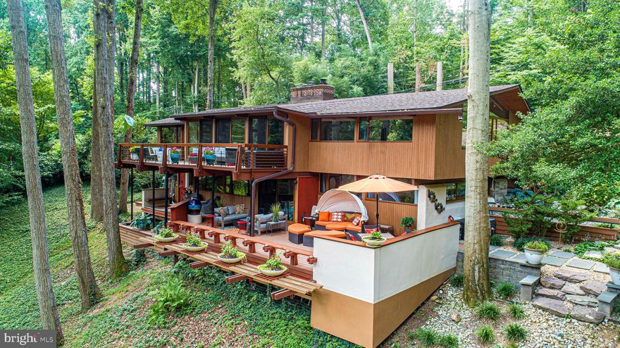 Welcome to this exquisite 1971 Acorn Deck House. This mid-century modern-inspired Deck House
sits on a private one-acre wooded lot backing to parkland above the Loch Raven Reservoir. The post-
and-beam home has been a complete top to bottom custom renovation by its Architect owner, who
has meticulously restored and maintained the home and is now proud to present it to the market.
Deck House as a company was founded in 1959 by William Berkes and Robert Brownell. Both
worked as young architects focused on building prefab Tech-built houses; this was the beginning of
the Mid-Century modern movement. Modern technology combined with the organic principals to live
in harmony with nature as envisioned by Frank LLoyd Wright gave birth to the Deckhouse.
The company, still in existence in Acton Massachusetts as Acorn Deck House, describes the design
this way: “Deck House offers an efficient post and beam building system with exposed structure,
making a powerful statement of beauty, strength and function. Floor to ceiling glass frames connect
with the natural environment to create a feeling of living in the outdoors. Interior spaces flow freely,
accented by a rich combination of natural woods. Deck House is a quiet statement about one’s own
self-confidence – a home of relaxed elegance in perfect harmony with the natural world, inside and
out.”

With 3300 square feet of living space spread across two levels of architectural excellence, offering
three bedrooms and two fully renovated bathrooms, this property offers the perfect combination of
style, space, and comfort. As you step inside, you'll be impressed by the incredible build quality and
attention to detail that's evident throughout the home. The exposed beams, cedar roof deck, and solid
mahogany doors and windows are a hallmark feature of the Acorn Deck House; together they add to
the sense of grandeur and sophistication. The large windows invite natural light to flood the space,
creating a bright and airy ambiance. The design emphasizes the connection to nature; every wall has
expansive open glass walls that overlook into the forest of tall red oak, white oak, hickory, and tulip
poplar trees. The change of seasons become the walls –natures art that make this home truly
integrated inside and out.

The tastefully decorated interior boasts clean lines and a minimalist aesthetic that perfectly
complements the mid-century modern architecture. The open-plan living areas are perfect for
entertaining guests or spending time with your family, while two cozy fireplaces creates a warm and
inviting atmosphere on chilly evenings. The updated kitchen features stainless steel appliances,
granite countertops, an entertaining island, and ample storage space, making meal preparation a
breeze. There is also a side coffee and cocktail prep area with eat-in breakfast table; this leads you to
your outdoor dining room right off of the kitchen, with easy access to your outdoor grill. This is an
entertainment gem.

The bedrooms offer plenty of privacy and relaxation, while the recently updated bathrooms boast
luxurious finishes and fixtures including features like a soaking whirlpool overlooking the gardens that
exudes sophistication. Custom tile and wallcoverings accent walls to warm the interior architecture.
Outside, you'll find a serene and peaceful setting, multi-level garden spaces and decks are nestled
among the trees and mature azaleas’, where you can relax and unwind while enjoying the natural
beauty that surrounds you. Each side of the house has custom designed deck spaces where the
entire family can find a place to enjoy alone time or large gatherings. Private cul-de-sac; 5 min to I695, 10 min to Towson shops, 15 min to wineries—trails just 0.25 mi away!

This 1971 Acorn Deck House is an exceptional property that offers a unique combination of luxury,
style, and comfort. If you're looking for a spacious and elegant home in a tranquil setting, this is the
perfect property for you.