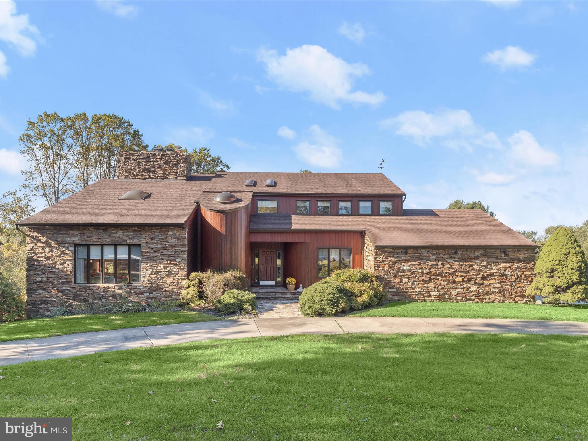 Set on a picturesque corner lot in the highly desirable Greenlands community of Phoenix, MD, this custom-built Frank Yockey residence is a true architectural gem on a sprawling three-acre estate. The striking Sikkens cedar and Marriott stone exterior blends seamlessly with the natural landscape, creating an unforgettable first impression.
Inside, the home is thoughtfully designed with four spacious bedrooms on the upper level, three and a half baths, and abundant skylights that fill the spaces with natural light. At its heart is a dramatic two-story, dual-sided stacked stone fireplace that serves as a breathtaking focal point, anchoring the living room below while adding warmth to the loft retreat above. From the loft, enjoy sweeping views of the vaulted living room, where wood beam ceilings, hardwood floors, and a wall of windows create a bright and inviting atmosphere.
The heritage-inspired kitchen features cherry oak cabinetry, double wall ovens, a cooktop, and a cozy eat-in area. French doors connect the kitchen to the formal dining room, making it perfect for gatherings. A family room, convenient main-level laundry, and a full bath complete the first floor, while French doors from the kitchen open to a covered outdoor dining space.
Outdoor living is equally impressive, with a multi-tiered deck that overlooks the landscaped rear lawn and a backdrop of mature trees, offering privacy and tranquility.
The primary suite is a true retreat, featuring a cathedral ceiling, a private section of the deck, and its own stacked stone fireplace. The spa-like en-suite bath includes a jetted soaking tub, a separate water closet, and a skylight that bathes the space in natural light.
The finished lower level extends the home’s versatility with a walkout, wood parquet flooring, a rustic stone wall with a wood stove, and a media room with Murphy bed and bar; ideal for entertaining or hosting overnight guests. A full bath adds convenience to this level.
Offering timeless architecture, elegant design, and a rare blend of indoor and outdoor living, this exceptional Greenlands home presents an unparalleled opportunity to own a private retreat in one of Phoenix’s most sought-after locations.