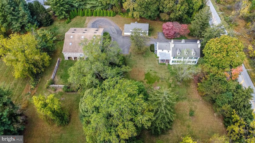 *Historic Lukens Manor* This extraordinary Circa 1815, 5 bedrooms, 2.1 bath Pennsylvania Federal Farmhouse has been elegantly restored to its original grandeur overlooking the 2.3-acre private lush grounds with a circular driveway and high velocity Central Air. This enchanting residence is accented with warmth, character, deep window sills, an abundance of natural sunlight and detail created by the original master craftsmen throughout. There are 7 decorative fireplaces, the kitchen walk-in fireplace was originally used for cooking, there are beautiful wide plank floors, high ceilings and 2 stairways. The original interior doors on the first floor are cherry and pine doors on the second level both include the original period locks and brass knobs. The magnificent 2 STORY STONE BANK BARN is absolutely stunning, it has been renovated and is possibly a perfect space for an artist studio, a personal collector or gym. The lower level of the barn could offer space for a car collector. The separate C 1827 carriage house has electric heat split air conditioning and could provide excellent space for a workshop or possible in-law suite including an upper level and power room. This sunny home features timeless elegance, the central hall entry is accented with portions of artwork believed to be painted by the itinerant artist for the wealthy Lukens family and a grand staircase with a cherry railing. The warm and inviting living room is accented with deep window sills, wide plank wood floors, a gorgeous fireplace surrounded with King of Prussia marble and a detailed wood mantel, the elegance of the spacious dining room is highlighted with original wide plank wood floors, a fireplace and views of the picturesque setting, a perfect place to entertain holiday guests or quiet family dining. The country kitchen features the original walk-in cooking fireplace, cherry cabinets, dishwasher and gas cooking, a spacious comfortable family room and an expansive mud room/laundry room which includes Mercer tile floors, a powder room, extra storage and entry to the rear covered porch complete this level. The 2nd level offers the primary bedroom wing with a full bath and entry to the back staircase; there are 4 spacious additional bright and airy bedrooms and a hall bath. The 3th level includes 4 additional rooms which are unheated but have central air. The high velocity air conditioning was installed on all 3 floors in 2019, the 200-amp electrical service was updated in 2025 and the electric hot water heater was installed in 2020. Heater is gas hot water. [Heater is gas powered furnace with hot water baseboard on 1st floor & radiators on 2nd floor) The Pennsylvania stone bank barn offers soaring ceilings, oversized custom windows and skylights, exterior barn doors slide back to reveal French doors that allow additional light and industrial ceiling fans to increase air flow, split units for heat and air conditioning[electric mini-splits are installed in lower level of the barn; 4 gas furnaces heat the upper level]. The barn and carriage are being sold as is condition. There is an extraordinary amount of property for a pool, play areas or outdoor entertaining in this park-like setting. Conveniently Located with easy access to PA Turnpike, Septa Train to Center city, shopping centers, restaurants, downtown Ambler’s Festivals, Theater and Playhouse. Sought after upper Dublin Schools.
