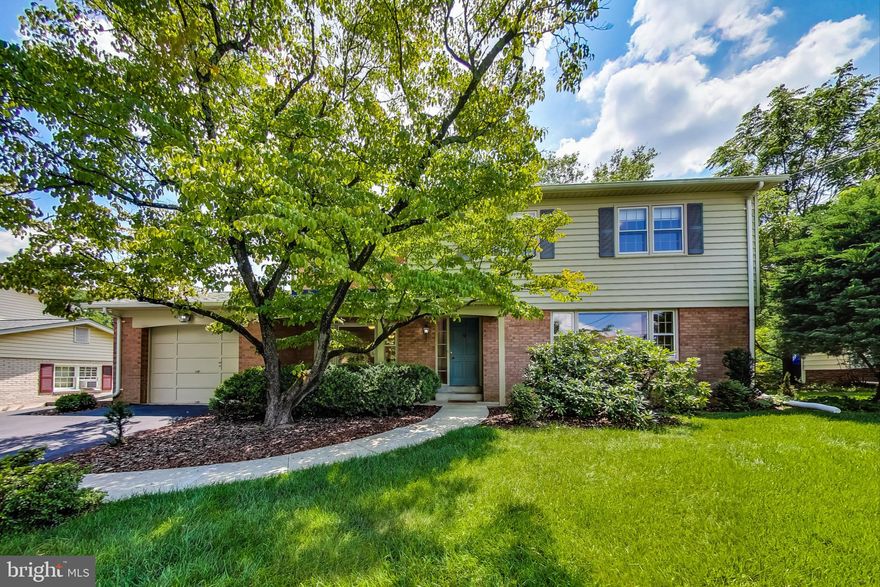 Welcome to this delightfully retro home in the quiet neighborhood of Springbrook Village of Silver Spring. Front and back yards gently slope away from the house and are lush with mature trees and flowering shrubs.  Hardwood floors throughout the main and upper levels have been well maintained by the original owner. The Living Room and Family Room both feature large picture windows.  This home is full of light!  A beautiful candelabra chandelier warms up the Dining Room.  The bright Kitchen accommodates a cozy Breakfast Nook overlooking the back yard with a patio for outdoor relaxing and entertaining.  The cozy Family Room, with new LVP flooring, features a wood-burning Fireplace and leads to the single-vehicle Garage where there is enough extra space for lawn equipment and to add a workbench or cabinets.  The asphalt driveway makes room for three additional cars.  The main level also includes a convenient Powder Room with glazed ceramic tile walls and ceramic mosaic floor.  Four bedrooms upstairs offer roomy closets with sliding doors for easy access.  The en suite Master Bath and the Hallway Bath (with Laundry Chute) are in mint condition and are reminiscent of the sixties with glazed ceramic wall and floor tiles.  A Master Suite closet provides access to the attic where an Attic Ventilation Fan helps in maintaining temperature balance.  The upper-level open foyer is large enough for decorative or functional furnishings.  The 1,171 SF Basement is tiled and features a Walk-out Stairs to the yard.  Washer and Gas Dryer are conveniently located near the Laundry Chute drop.  Major systems are recent: Roof-2015, A/C-2022, Furnace-2018.  An additional Refrigerator/Freezer contributes overflow room for chilled and frozen foods.  Consider the MLK Recreation Center an extension of your own back yard.  It's only an 8-minute walk, 3-minute bike ride, or 2-minute drive away.  Enjoy indoor & outdoor swimming, lazy river, weight room, tennis, basketball, baseball, exercise stations, fishing, HeartSmart Trail for walking, jogging & hiking, playground, and picnic areas. Some activities require fees, reduced for MoCo residents.  Other nearby attractions include Paint Branch Trail, Brookside Gardens, White Oak Library, and not to mention Washington, DC, Baltimore, and Annapolis which are easily accessible via MD-29, ICC-200, I-495.  Shopping, dining, entertainment, medical facilities, and houses of worship abound in the area. (By the way, NO HOA!)