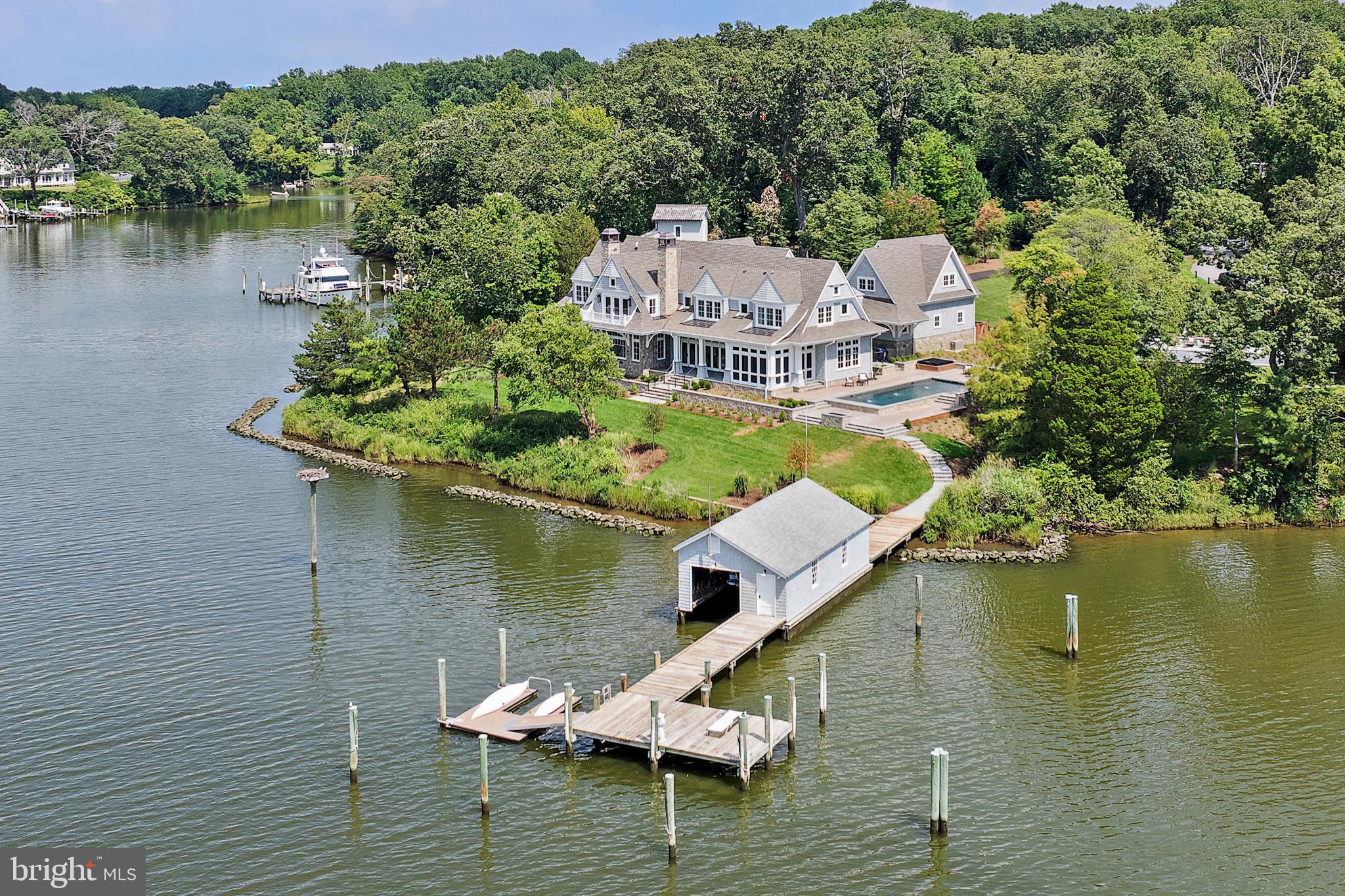 Experience sweeping waterfront vistas and unforgettable sunsets from this never-lived-in, newly completed luxury estate on 1.04 acres along the protected waters of Aberdeen Creek.
Designed by Hammond Wilson Architects and built by the award-winning Pyramid Builders, this custom residence was conceived to celebrate its extraordinary waterfront setting, where southwest sunsets reflect beautifully across the creek each evening.
With nearly 380 feet of shoreline, the property features a 125-foot private pier with 6’ MLW at mid-dock and 10’ at the end, plus three boat slips with water, electric, and lighting. A floating dock and rare boathouse with traveler hoist and lift provide both convenience and character—amenities seldom found today.
The grounds, envisioned by acclaimed landscape architects Campion Hruby, showcase an artful balance of natural beauty and elegant design. Lush plantings, custom stonework, fountains, and thoughtfully crafted hardscapes enhance the sense of arrival and frame breathtaking views at every turn.
Outdoor living spaces are designed for seamless enjoyment of the water. A heated saltwater pool with Ipe decking is accented by fountains and counter-current swim jets for both leisure and exercise, appearing to spill toward the creek. A Bluestone patio with gas fire pit, hot tub, and a screened porch with retractable NanaWall glass doors extend the living space outdoors, while the outdoor kitchen makes entertaining effortless. Whether relaxing by the pool, dining alfresco, or gathering around the fire, every experience is enriched by the waterfront setting.
Inside, interiors by Erin Page Pitts continue the theme of light and openness. English white oak floors, expansive windows, and carefully placed rooms ensure the water is always in view. The chef’s kitchen features Wolf appliances, dual islands, and a catering pantry, while a 1,200-bottle wine cellar offers sophistication for collectors.
Smart home technology provides modern comfort with Ketra lighting that mirrors natural light, Sonos surround sound, and custom AV throughout. Geothermal heating and cooling, NuCedar siding, and a 50-year architectural roof speak to efficiency and longevity. Car enthusiasts will appreciate the two-car attached garage with climate-controlled storage and a detached three-car garage with flex space and half bath.
This pristine, never-occupied waterfront estate embodies the pinnacle of Annapolis living—where world-class architecture, craftsmanship, exquisite landscaping, and endless water views combine to create a rare opportunity for waterfront living at its finest. Please DO NOT drive down private road without an appointment.