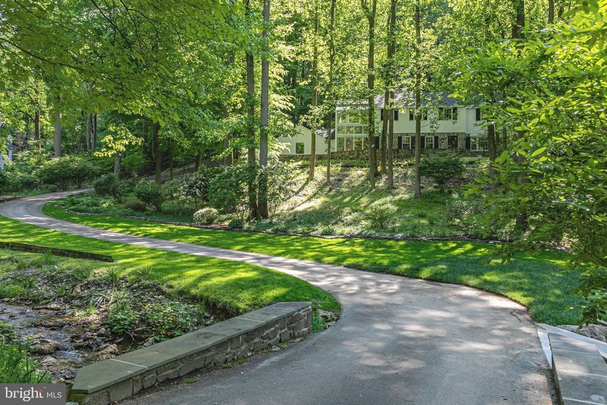 Stately traditional residence in a majestic estate-quality setting.  Perched upon a hillside offset by a significant stone veranda, towering woodlands, native plantings, it overlooks an active creek.  Its generously proportioned interior,  softly illuminated with dappled natural light,  offers verdant views from each of its abundant windows.  The outdoors are truly brought in with a 2 story glass botanical conservatory, planted with a variety of greenery.  A slate floored entry foyer, grand scale living room with a wood burning fireplace, formal dining room, library/family room,  breakfast room with glazed brick flooring, kitchen, butlers pantry, greenhouse laundry/mudroom and half bath on the main level are unified by hardwood flooring and provide excellent flow.  The primary bedroom suite containing an open contemporary bathroom (soaking tub, shower stall, double sink) and private deck, a 2nd bedroom suite with a dedicated bathroom, bedrooms 3 & 4 and a third full bath in the hall complete the upstairs level.  Located in the highly ranked T/E school district with great proximity to commuter routes, transportation, numerous green spaces and parks, restaurants, shopping and conveniences.  Full roof replacement 2023,  Stucco removal on garage and replaced with siding 2023, Exterior and interior paint 2023/2024, water heater replaced with tankless unit 2024