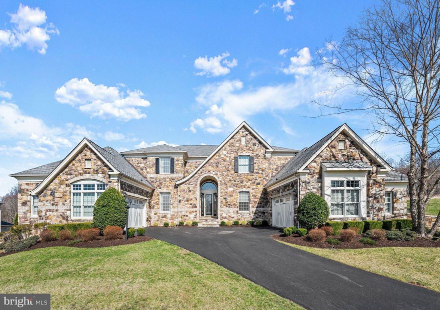 Enlightened Design & Luxury Living
With up to the minute finishes, an open floor plan, and extraordinary designer lighting, this residence is truly an artful experience, ready for living and entertaining.   Elegance and thoughtful design with Toll Brothers quality include high ceilings, strong architectural moldings, and designer lighting.  Experiential living begins with an entry courtyard sided by four garages and a stunning stone front.  Inside, a perfectly scaled orb and crystal chandelier preside over a grand two-story foyer, accented with dual curved staircases that set the stage for details to follow. Improved with the highest quality, designer features, and amenities, a setting is created that is well suited for gatherings that are formal, or informal, large, and small. The open floor plan unfolds to and from a dramatic two-story dining room layered with light from clerestory windows and a feature beaded chandelier.
Adjacencies that encircle the central dining room include a richly finished library and a formal living room that is punctuated with a perfectly curated decorative chandelier and tray ceiling. Sun-drenched splendor in the adjacent Sun Room draws you in through multiple French doors, and walls of windows that stream light into the space with a Palladian window and vaulted ceiling. The circular floor plan seamlessly opens next to a generously sized Family Room embellished with a commanding coffered ceiling, media built-in, and a stone fireplace that is reminiscent of the stone front entry. The design unfolds yet again into a welcoming Chef’s Kitchen and Breakfast Room that is sided by French doors opening to outdoor experiential living. Two waterfalls create a spa-like feel on a custom paver dining patio enclosed by garden walls and iron embellishments. Professional stainless appliances inspire chefs’ creations while family and friends enjoy the view and flavor from the tiered island and breakfast bar.  Unifying design elements continue to the lower level and include an up-to-the-minute polished concrete floor, and designer lighting to enhance a trending vibe. A fully-equipped wet bar, second walk-up bar, and theater room are perfect for informal gatherings, while a sixth en-suite bedroom and second laundry will accommodate special guests, and provide lifestyle flexibility.  The lower level is completed with full daylight and a walk-out atrium door.  Come home to 9,000SF of luxury design, privacy, spectacular, work-at-home spaces, and flexible living in Howard County.